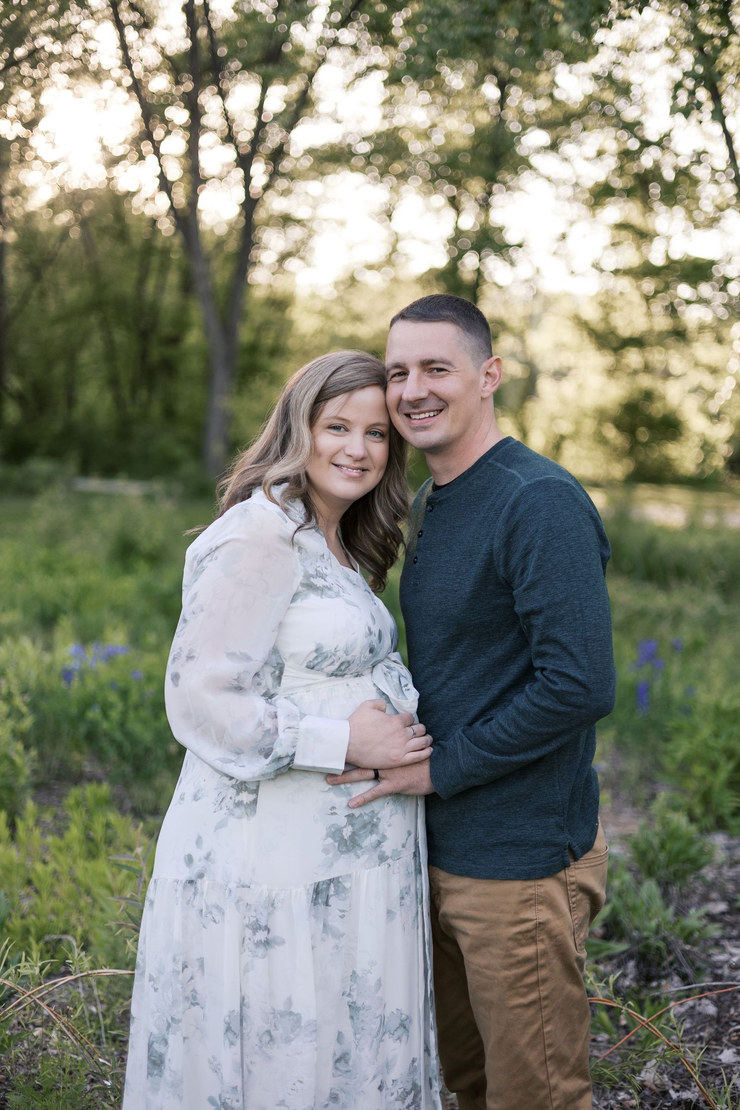 Smiling pregnant couple embracing outdoors at sunset for maternity portraits by Katy Rose Photography.