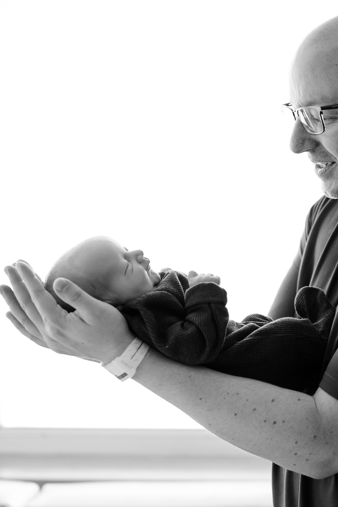 Artistic black and white silhouette of dad holding baby during hospital Fresh 48 photoshoot in Avon, Indiana by Katy Rose Photography