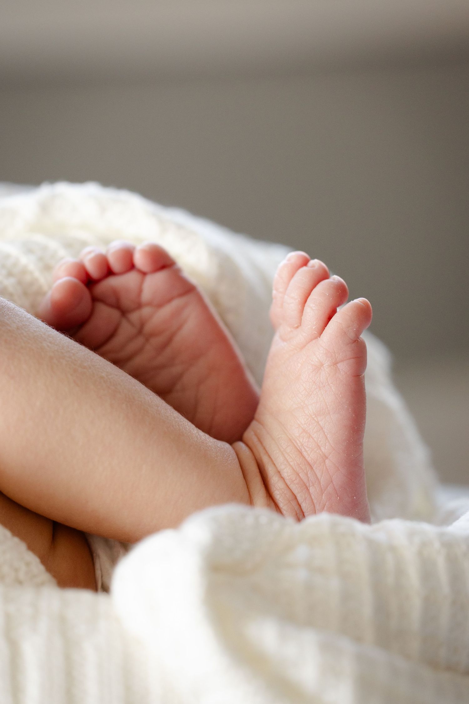 tiny baby feet resting on soft white blankets during in-home newborn session in Hendricks County