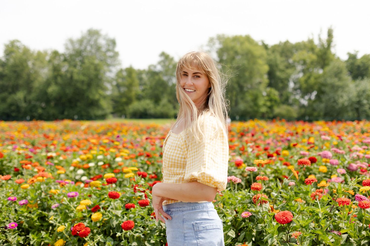 Woman stands among vibrant orange and yellow flowers in a summer field at Beasley's Orchard in Danville, Indiana by Katy Rose Photography.