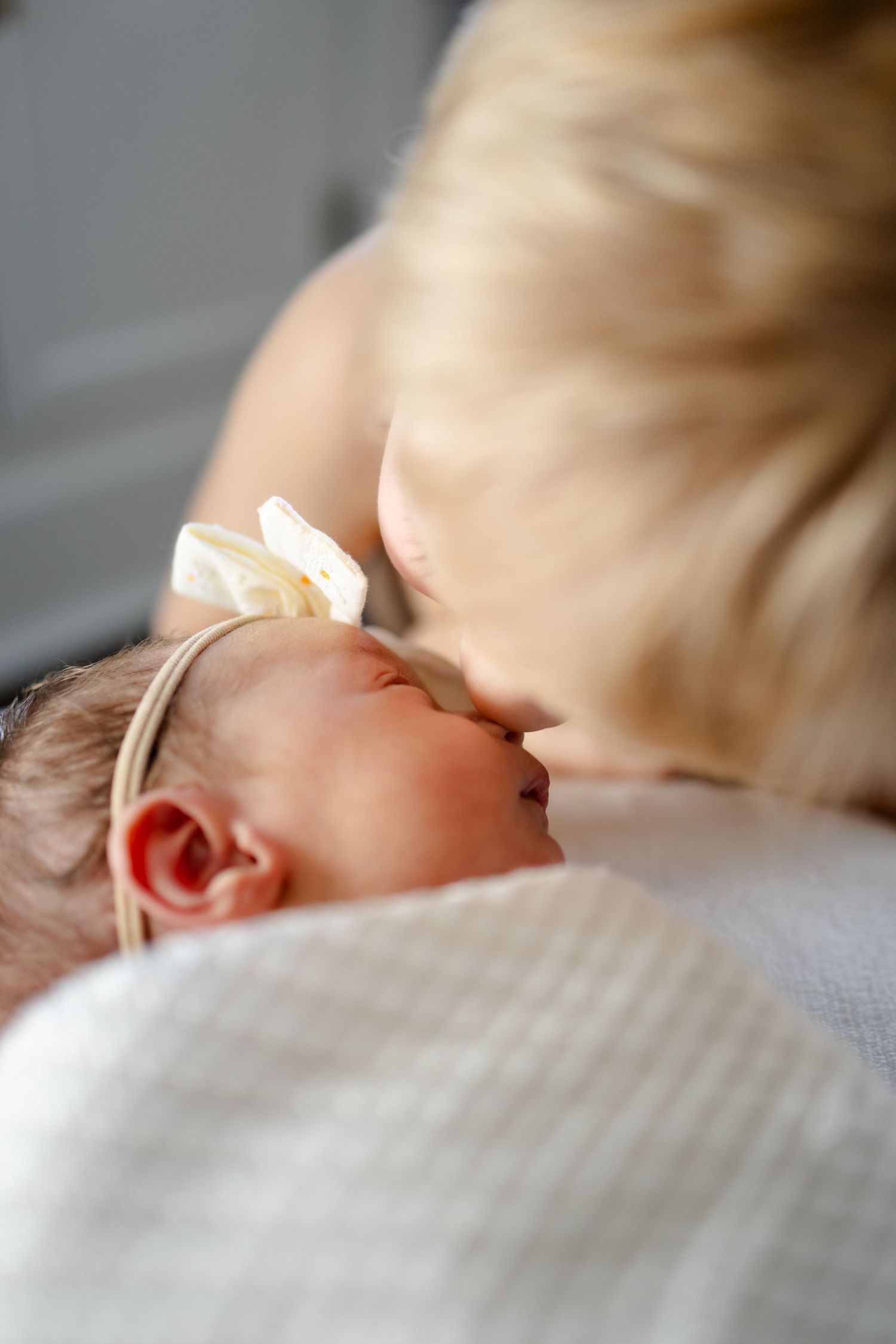 Close-up view of a sleeping baby's face with brother nuzzling her nose during newborn session in Mooresville, In by Katy Rose Photography