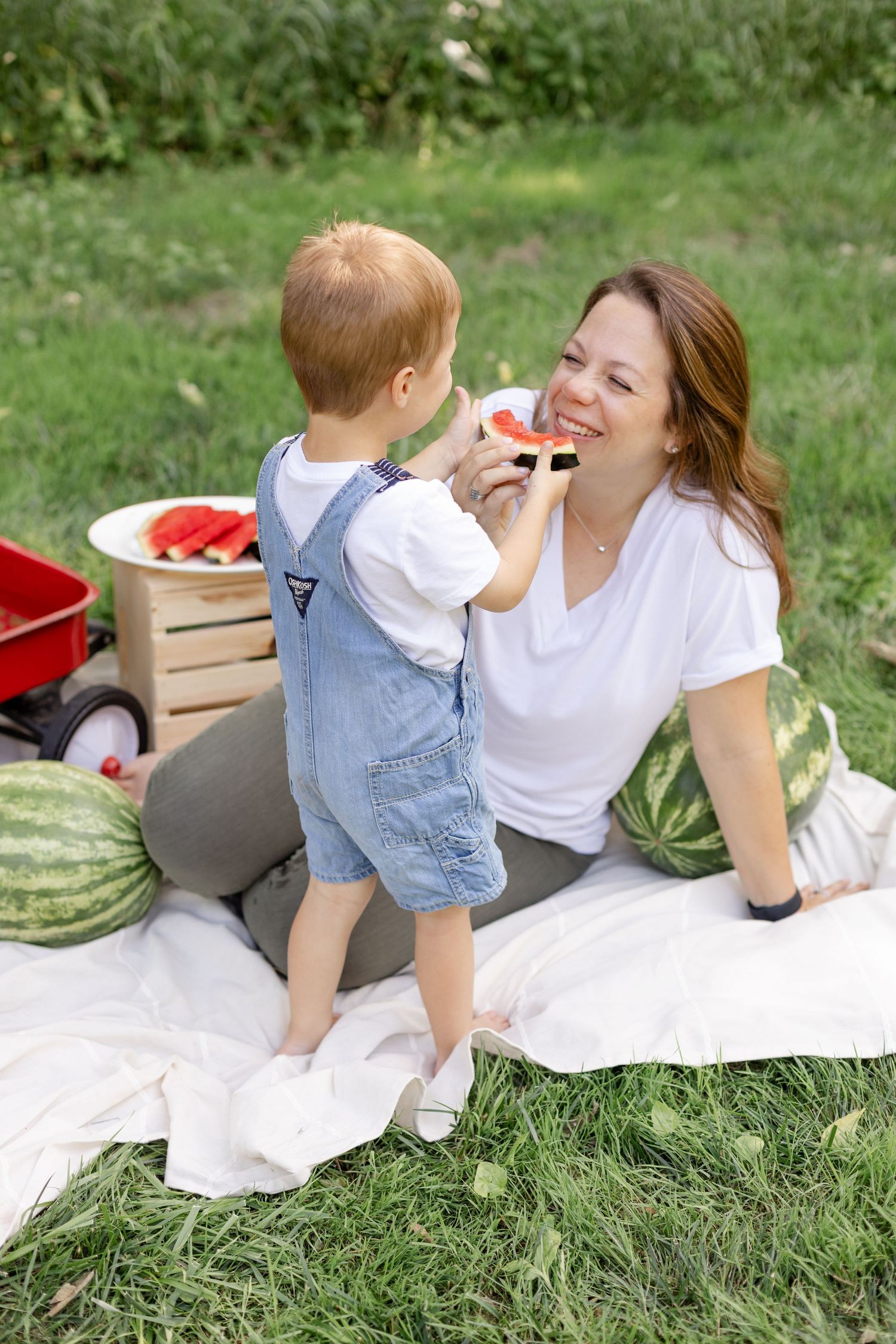 Mother and child sharing a sweet moment while having a watermelon picnic on grass during mini session at Arbuckle Acres in Brownsburg, IN