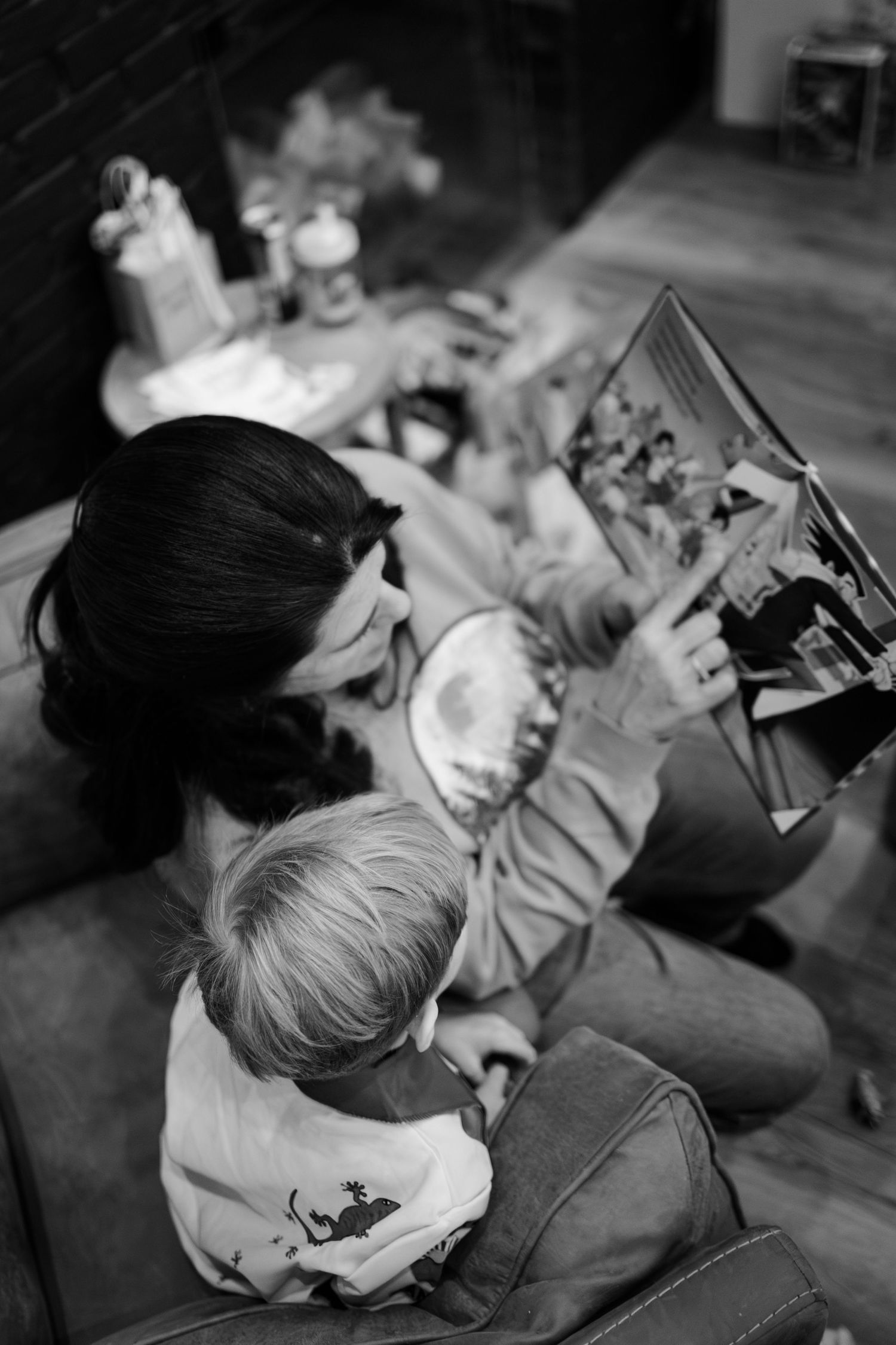 Black and white photo of reading time on a couch with a picture book during in-home lifestyle family photoshoot in Whitestown, Indiana.