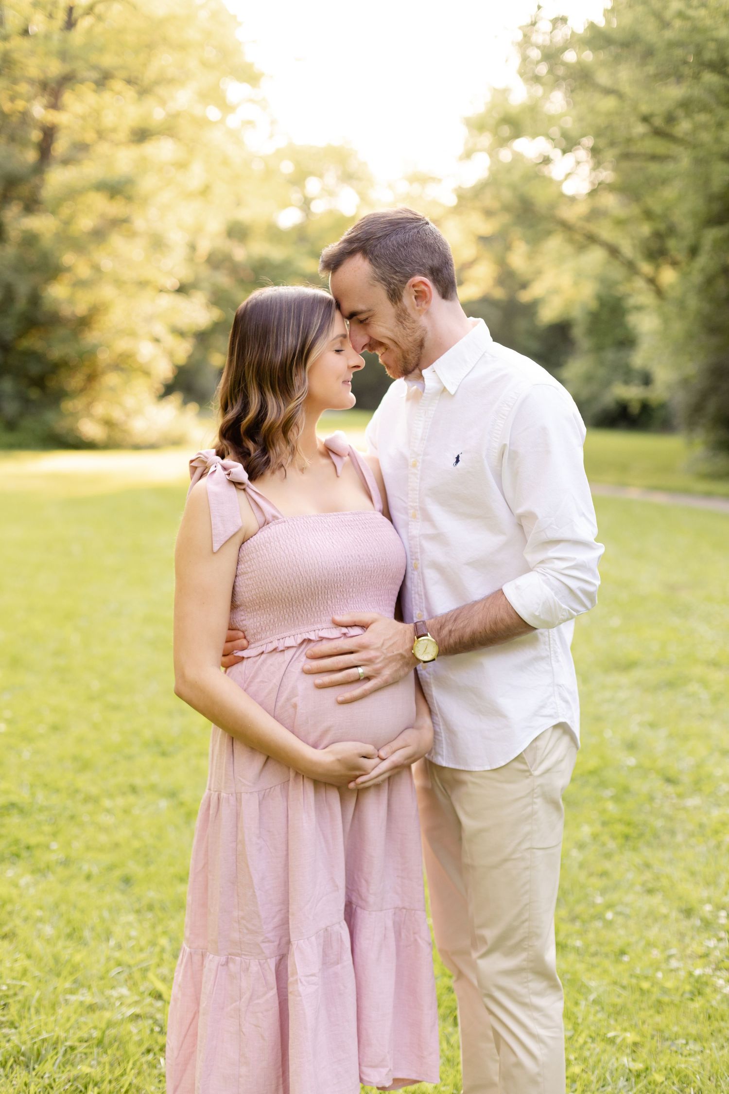 Sweet maternity moment between couple in coordinated pink and white outfits.
