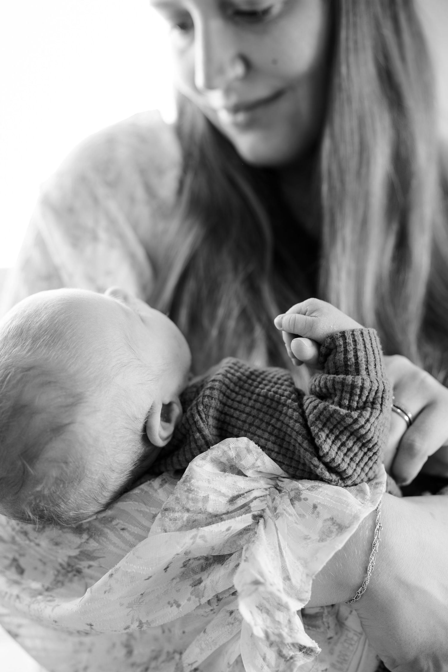 A tender moment captured in black and white as a parent holds and gazes at a newborn baby during in-home newborn session in Indianapolis