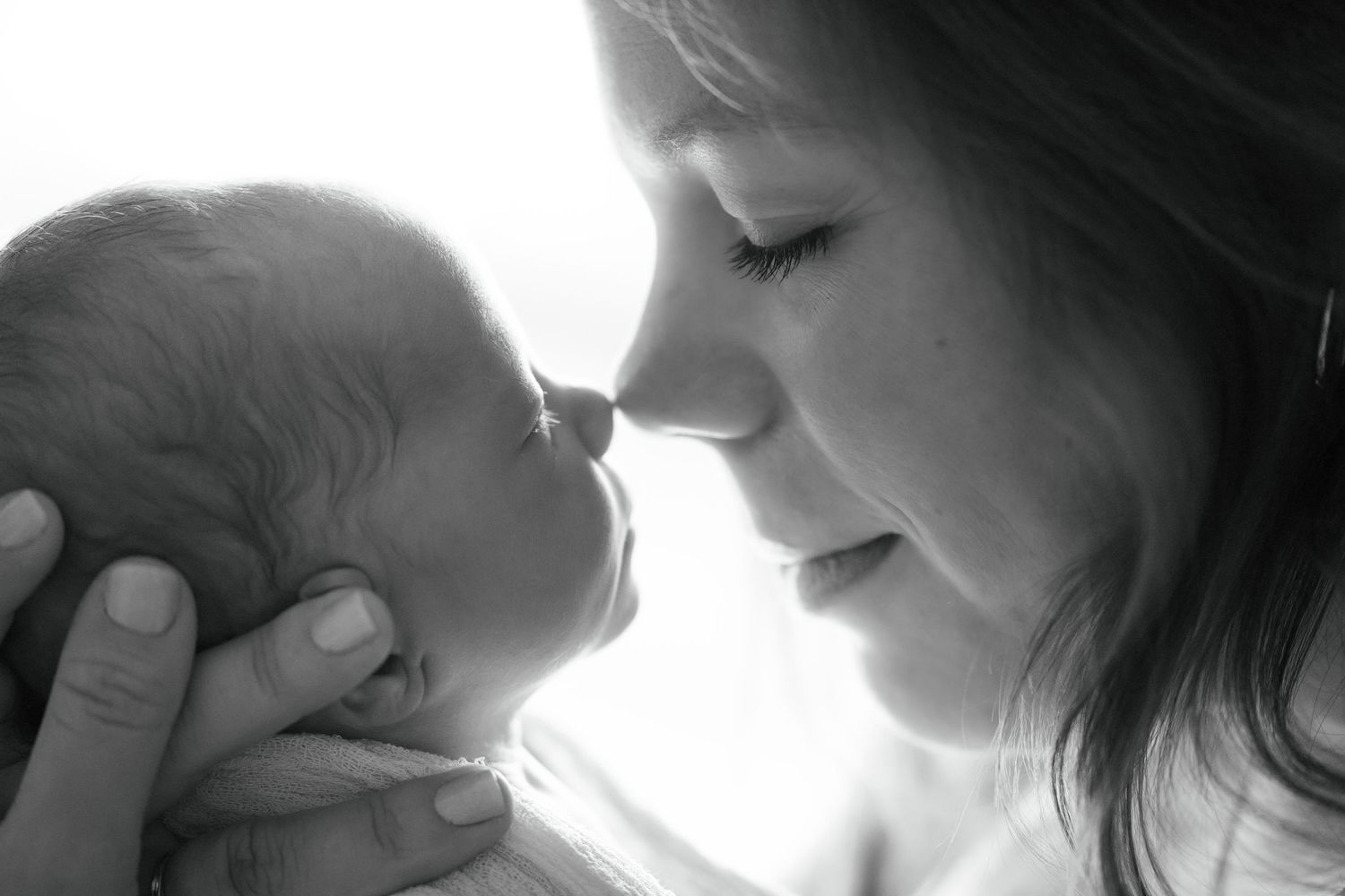 Black and white photo of a mother tenderly touching noses with her newborn baby during Brownsburg, Indiana newborn session