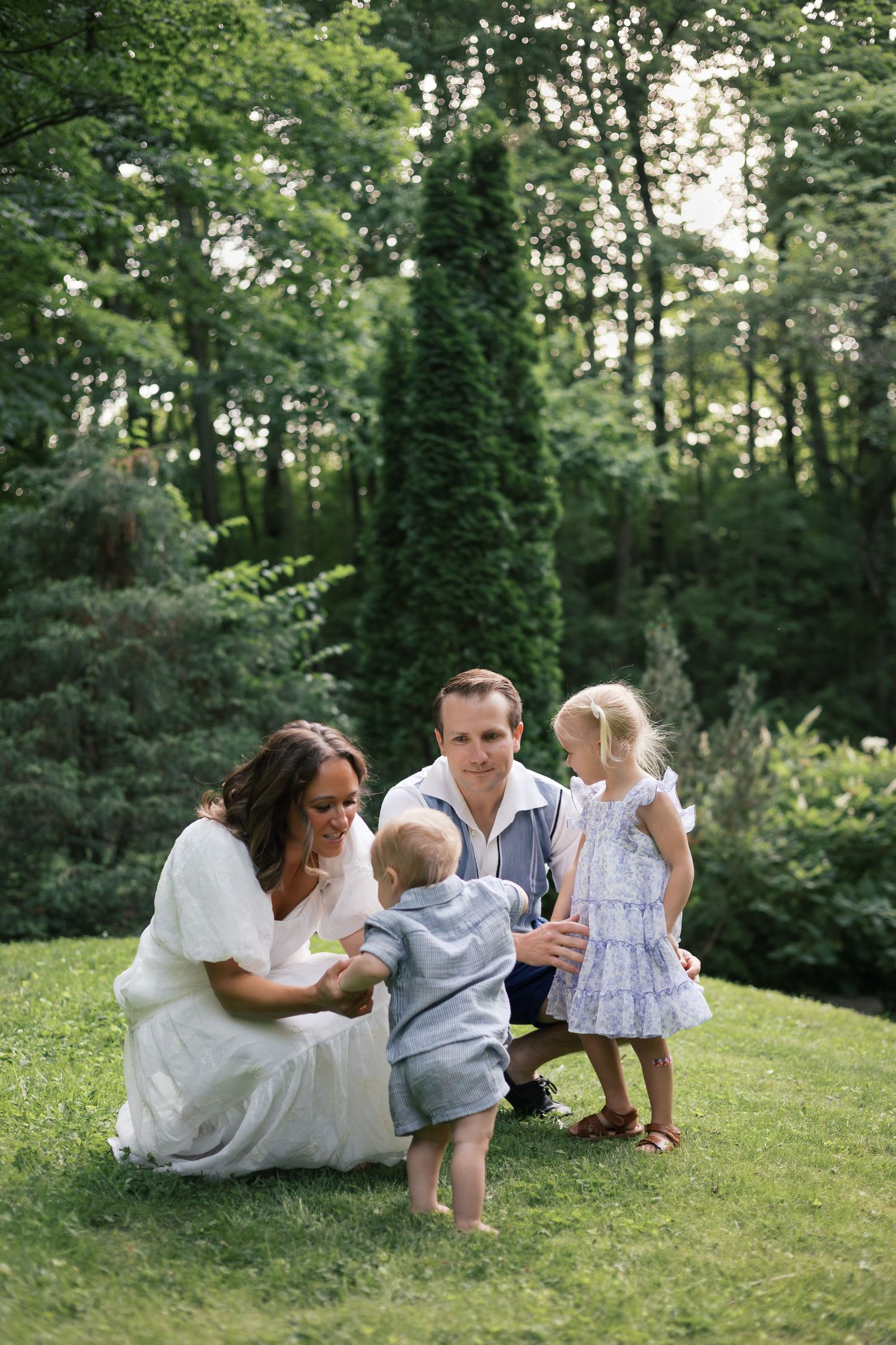 Family of four enjoying a sunny day on green grass surrounded by garden greenery for Indianapolis Family Photos by Katy Rose Photography.