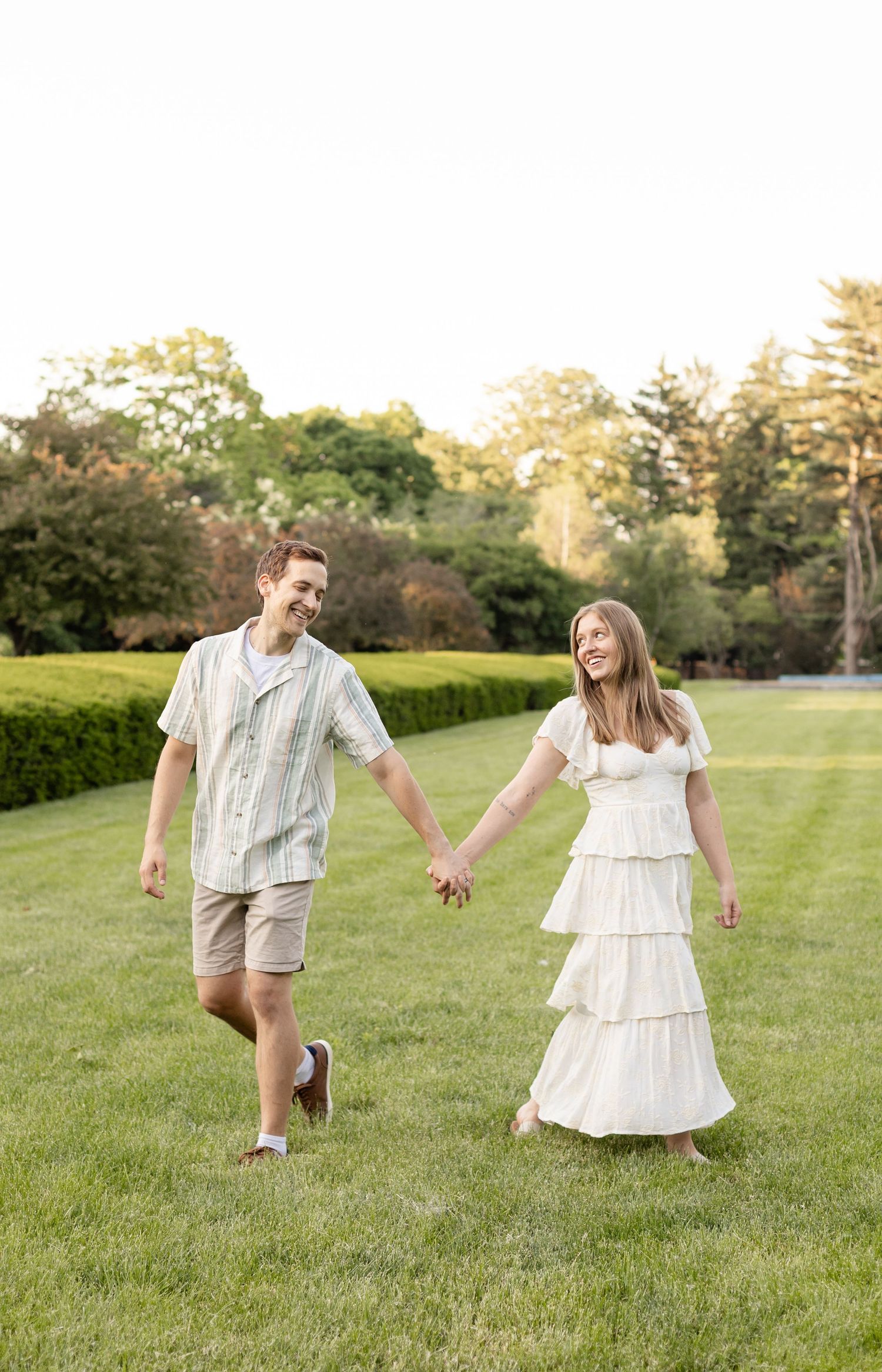 Mom & dad dancing and twirling on a grassy lawn at sunset during family photo session at Holcomb Gardens.