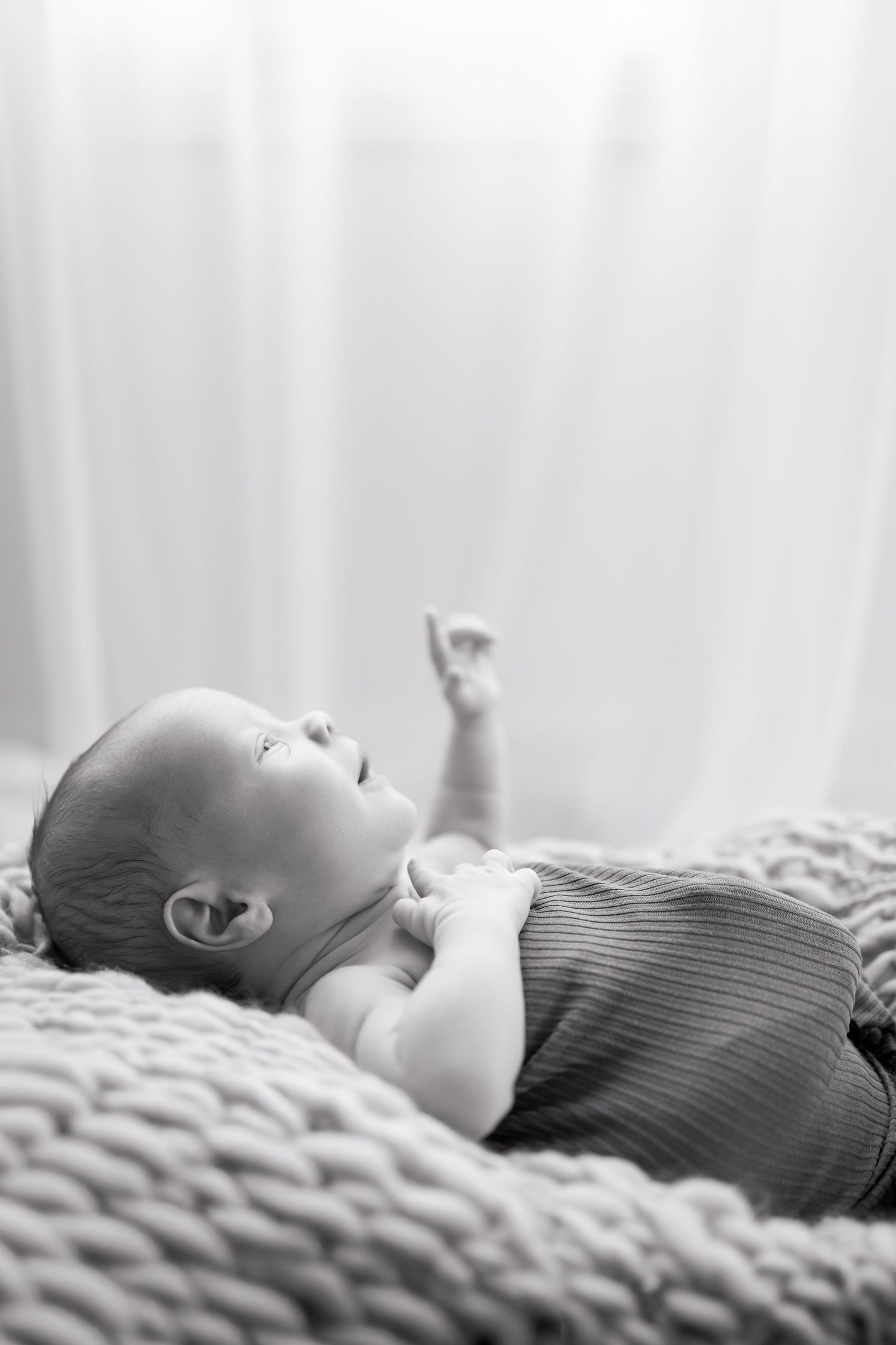 Black and white photo of newborn baby lying on a knit blanket during newborn photography session by Katy Rose Photography.