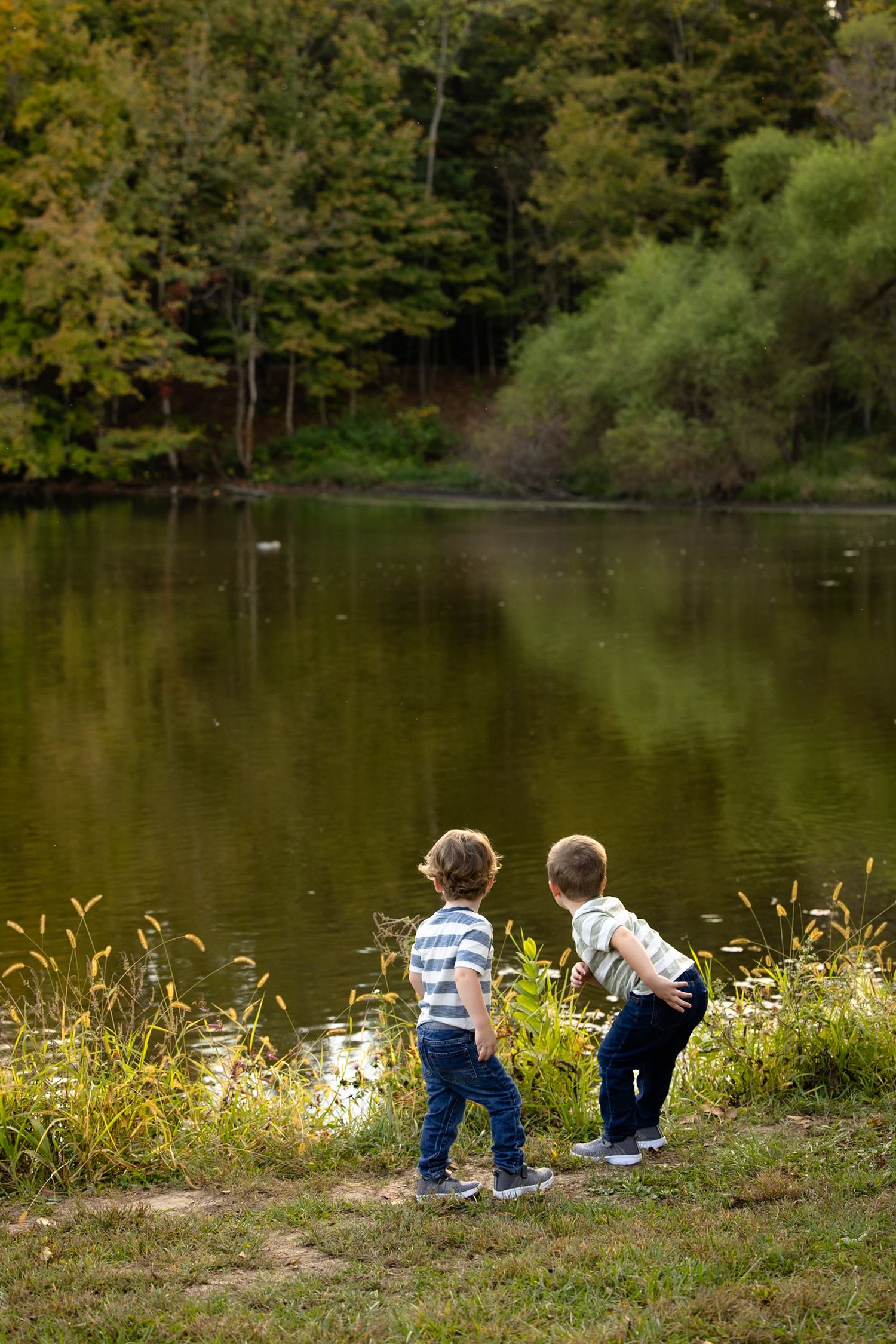 Two young brothers standing by pond during family portraits in Plainfield, Indiana by Katy Rose Photography