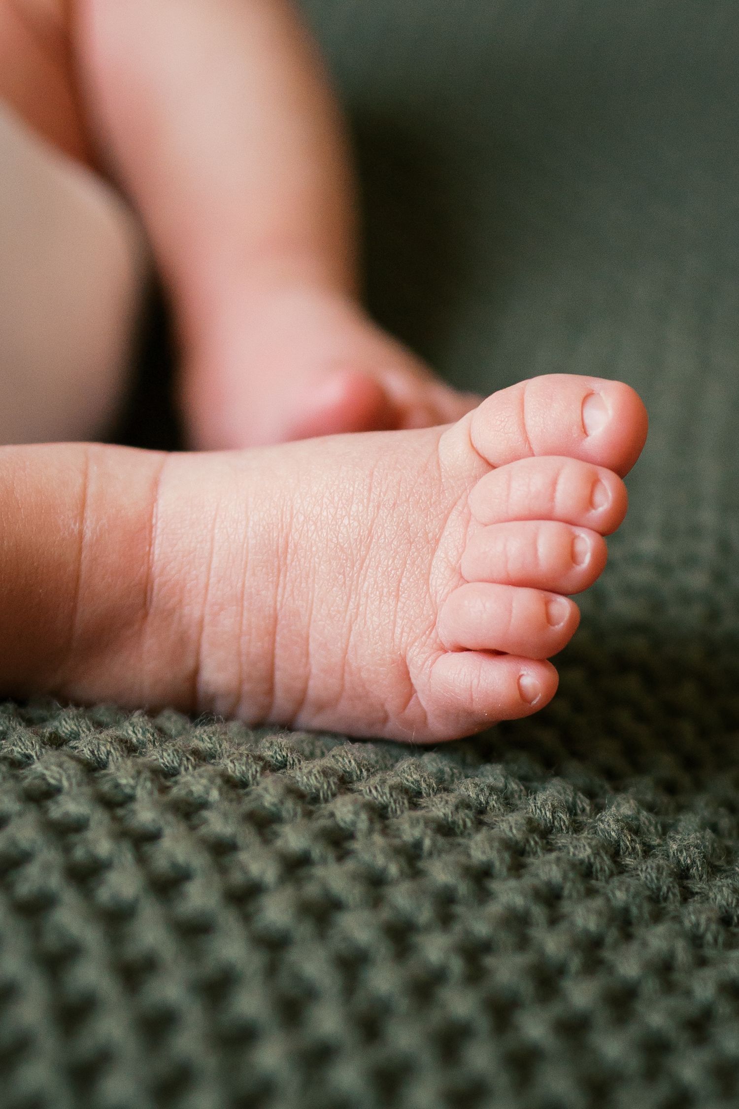 Close-up of tiny newborn feet resting on a soft green knit blanket during newborn session in Indianapolis by Katy Rose Photography.