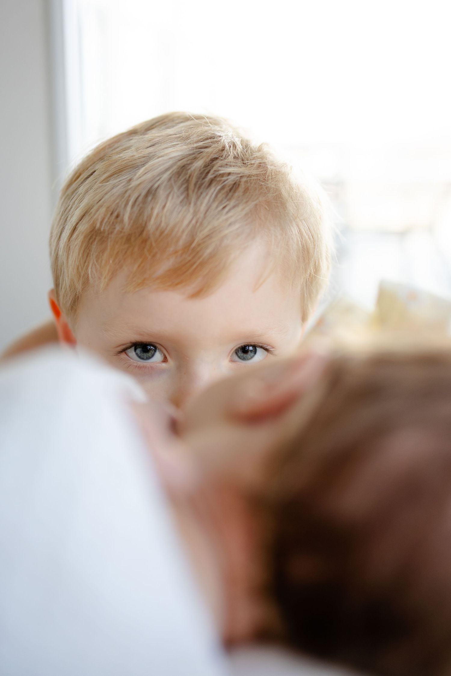 A close-up portrait shows bright blue eyes and blonde hair in soft window lighting during newborn session in Mooresville, Indiana