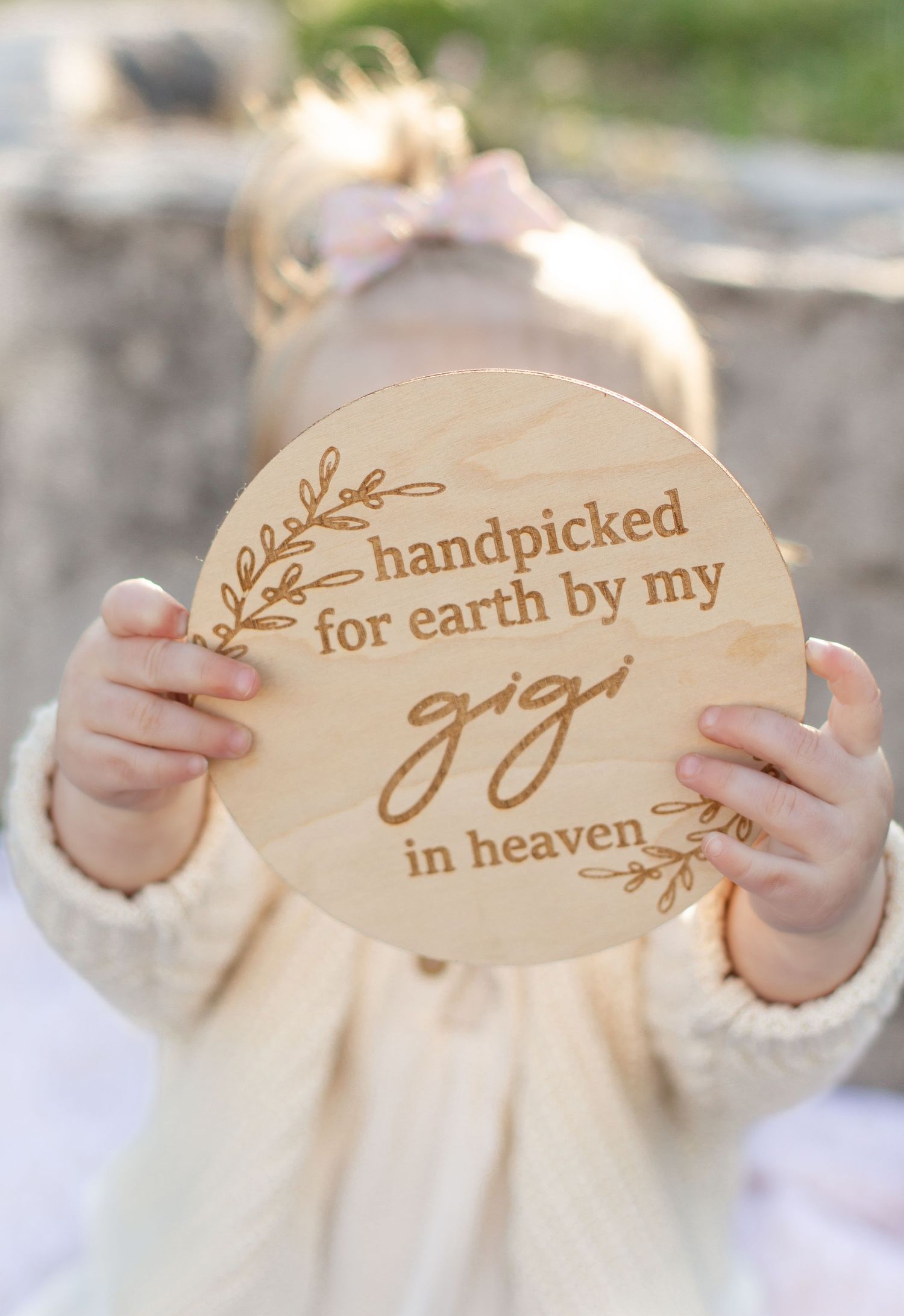Wooden sign with engraved text being held against soft natural background during family photo session in Indianapolis