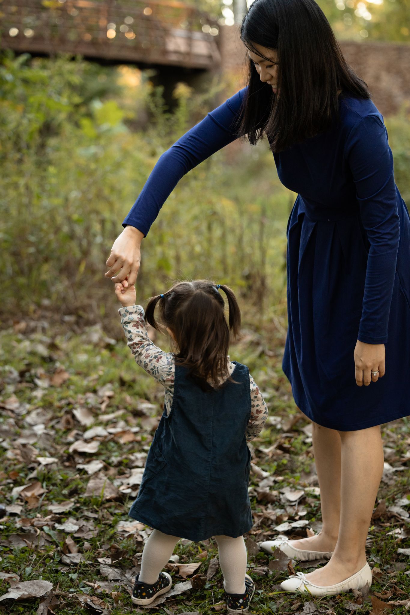 Mother twirling toddler daughter during family portrait session at Arbuckle Acres Park in Brownsburg, Indiana by Katy Rose Photography.