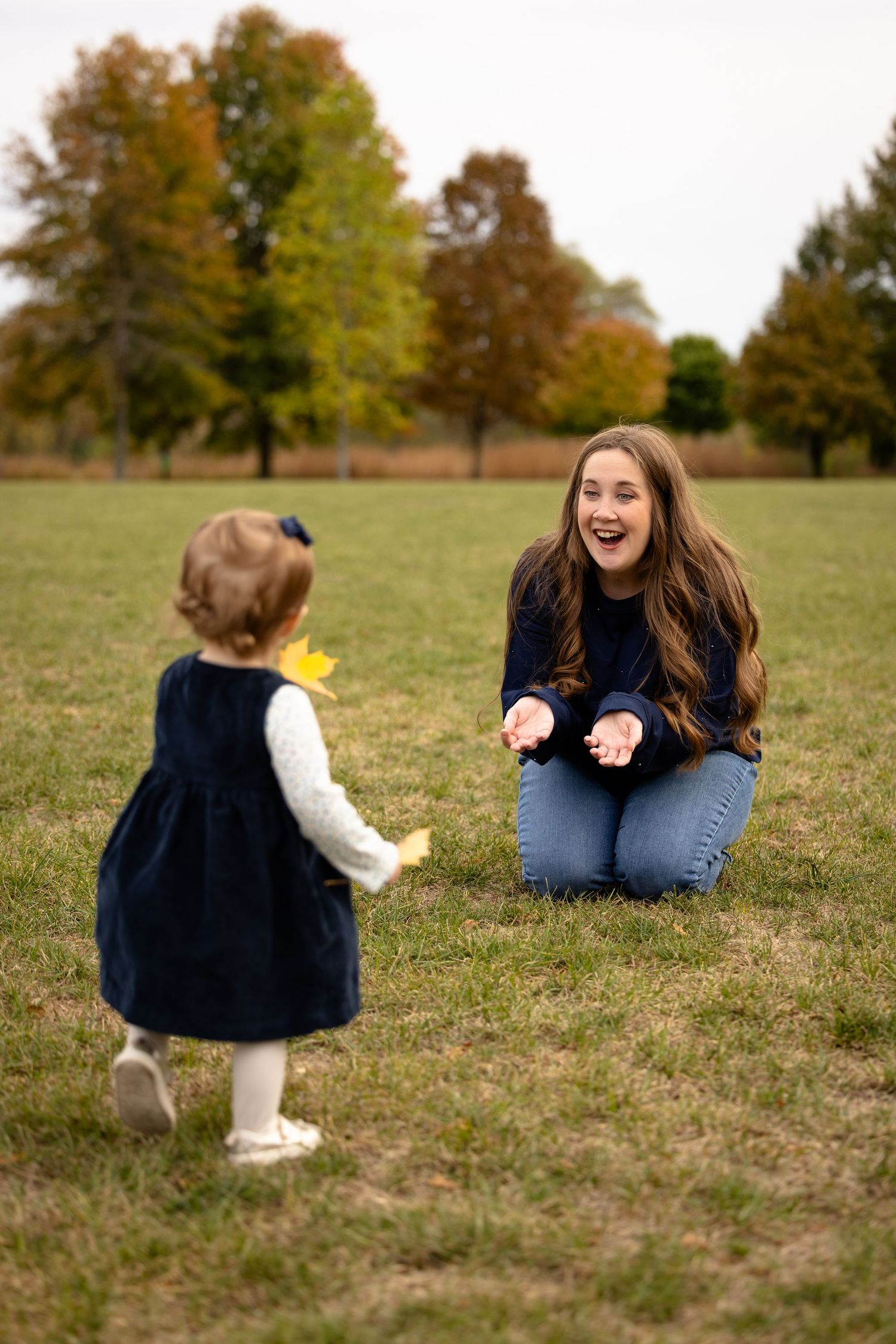 Mother and daughter playing in field during fall family photo session at Avon Town Hall Park in Avon, Indiana by Katy Rose Photography.
