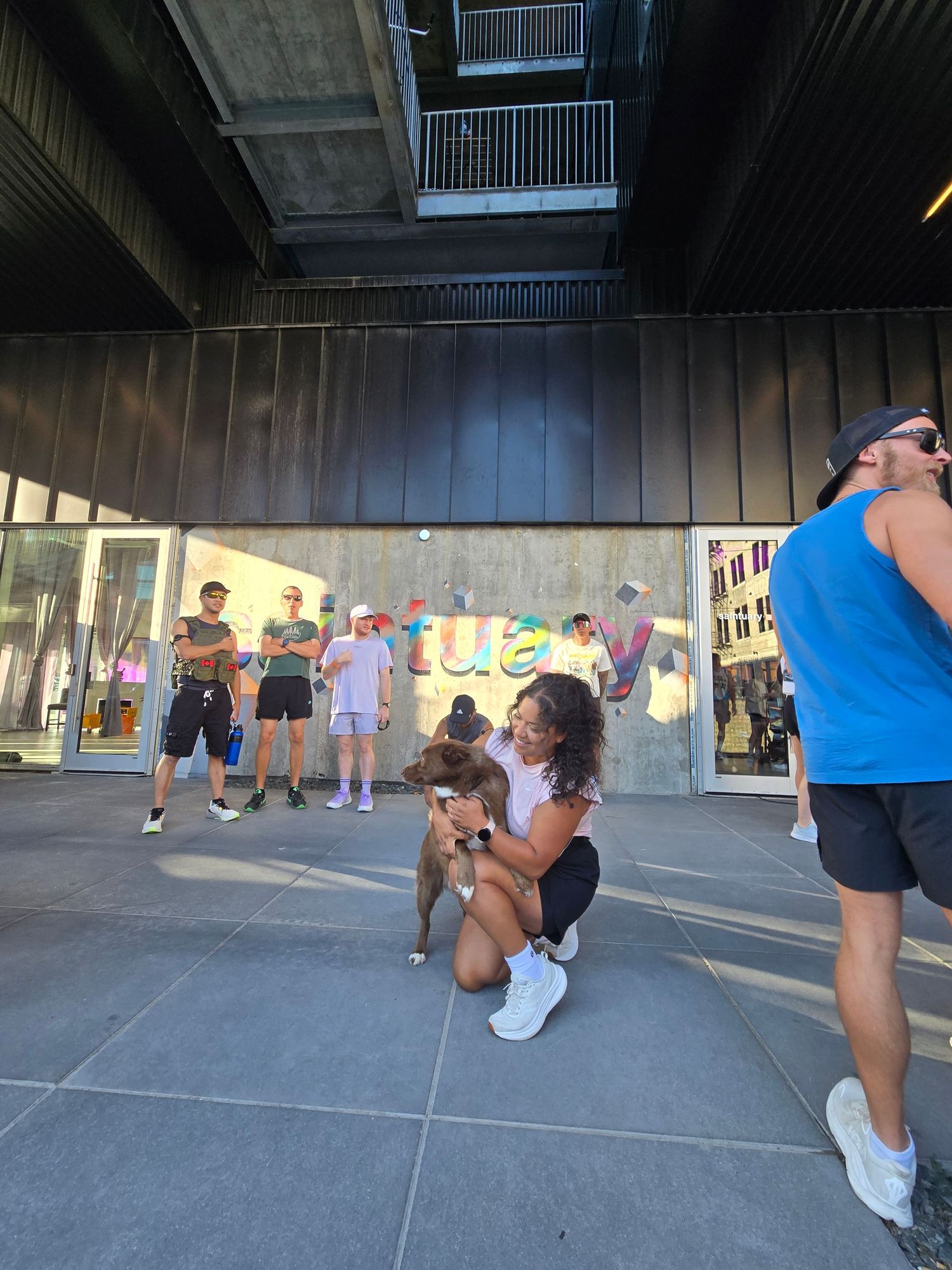 Young woman crouching with dog outside urban building with colorful street art.