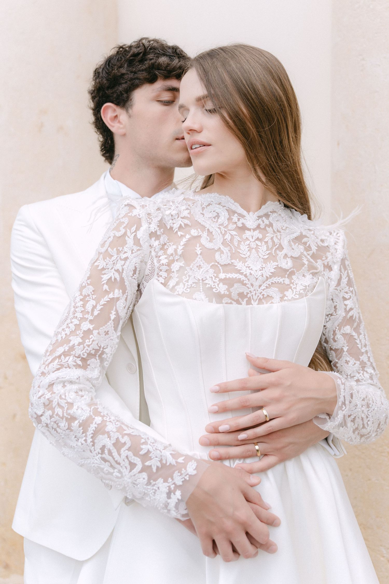 Romantic couple in white lace wedding attire embrace in a series of intimate poses against a light background. Villa Mosconi Bertani