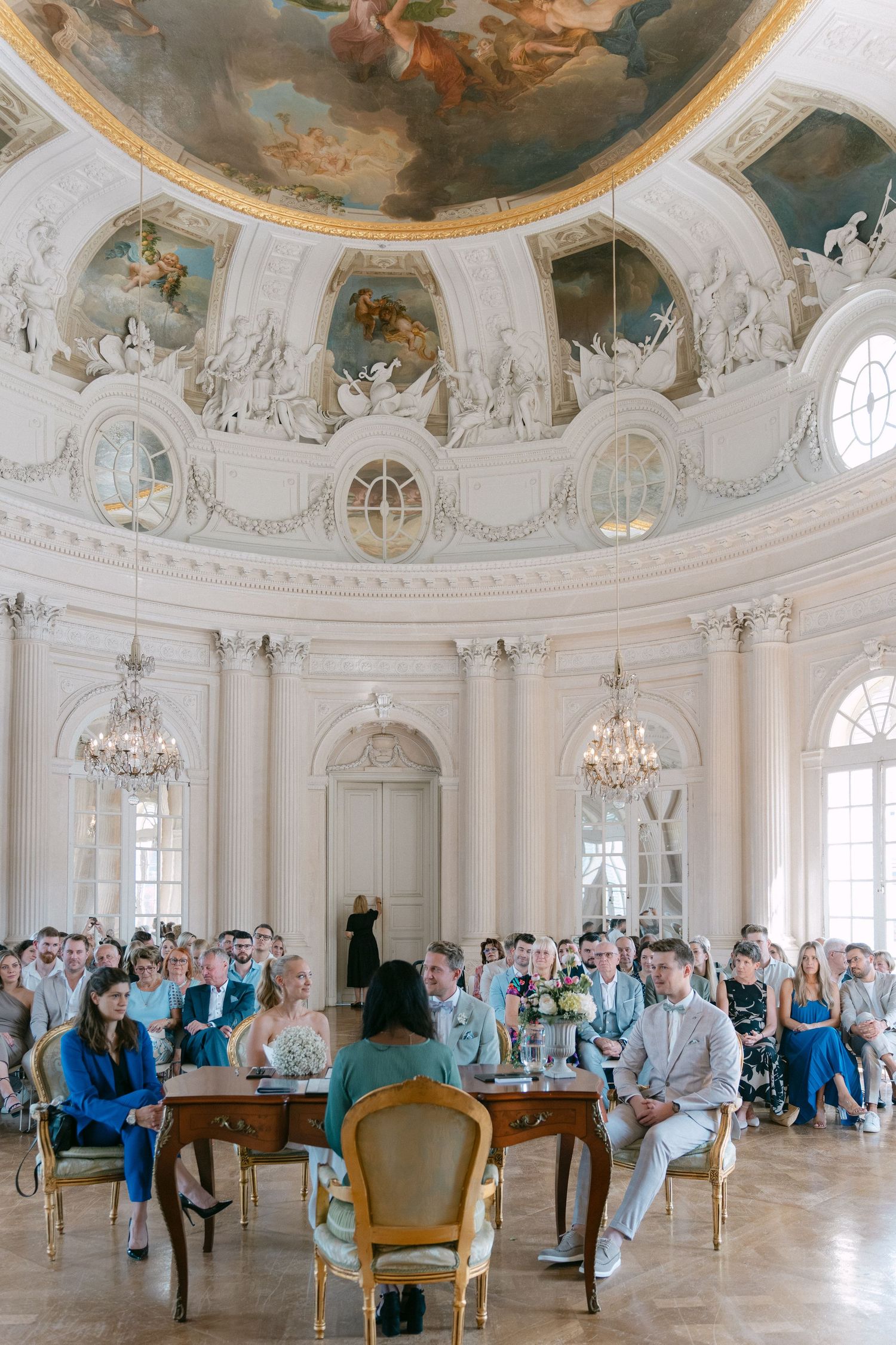 Elegant wedding ceremony in ornate baroque hall with painted dome ceiling and crystal chandeliers. Schloss Solitude