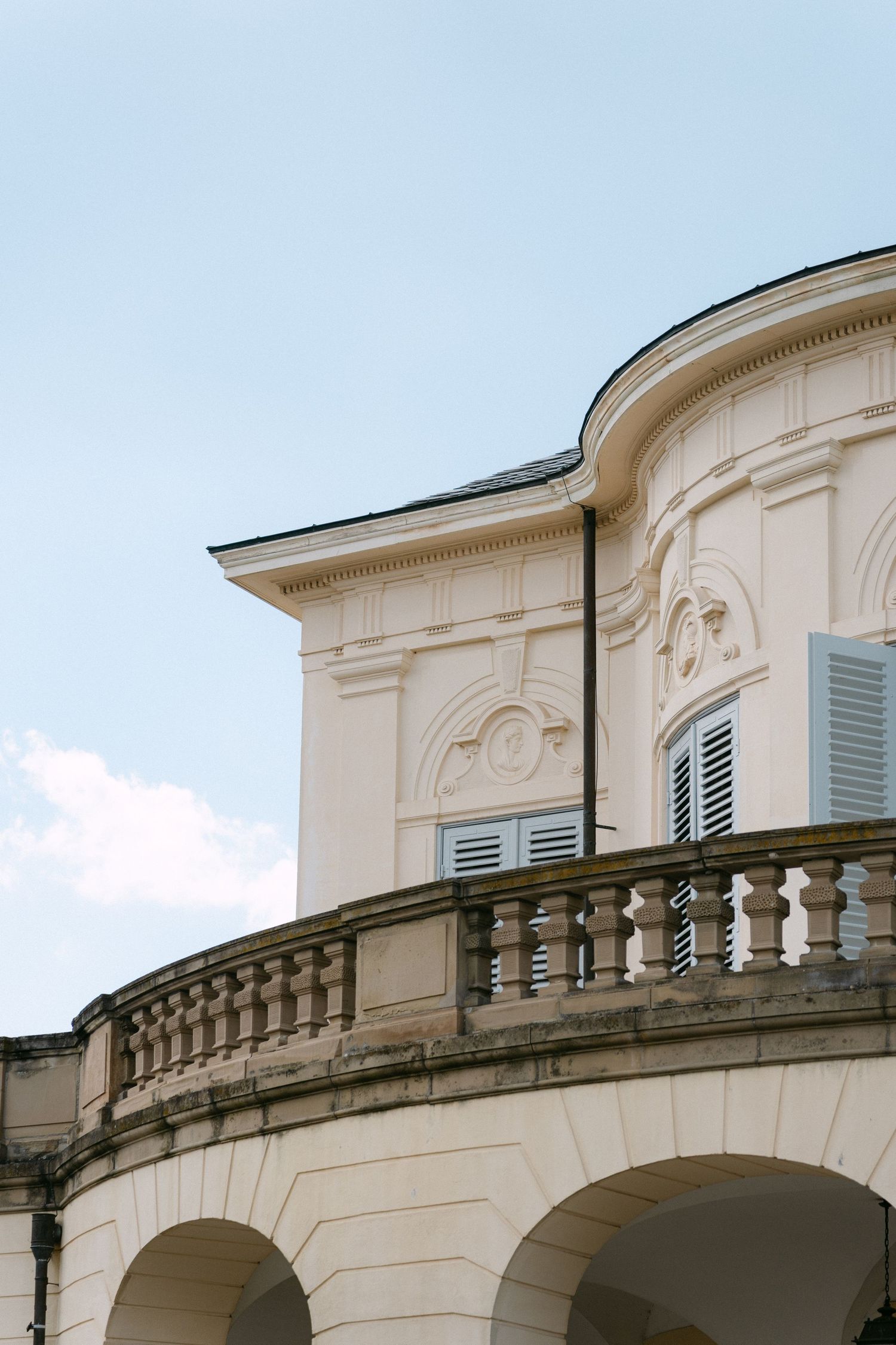 Ornate white Italian villa architecture featuring arched balconies and decorative moldings against a blue sky. Schloss Solitude