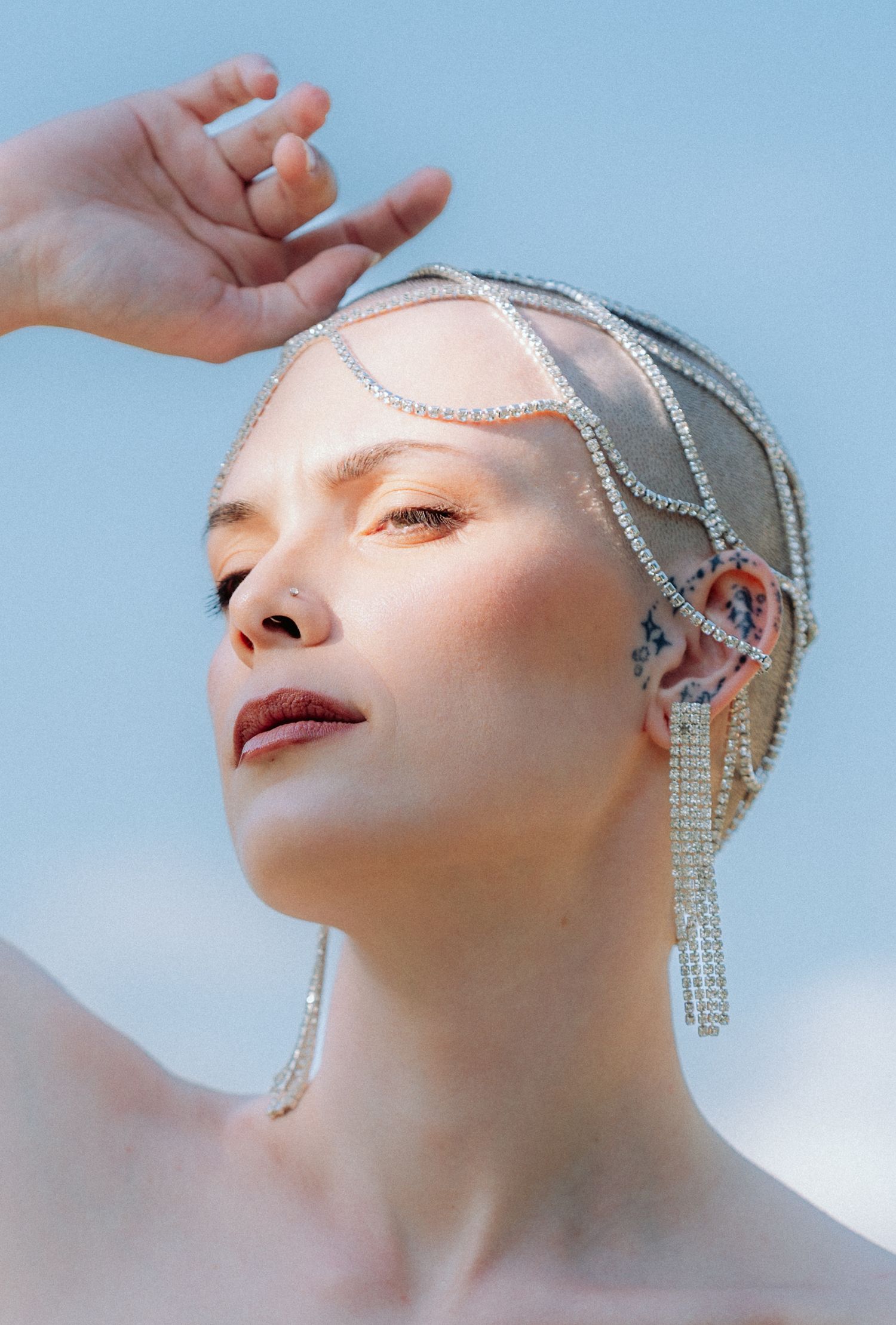Artistic beauty portrait featuring sparkling crystal jewelry against a soft blue sky background.