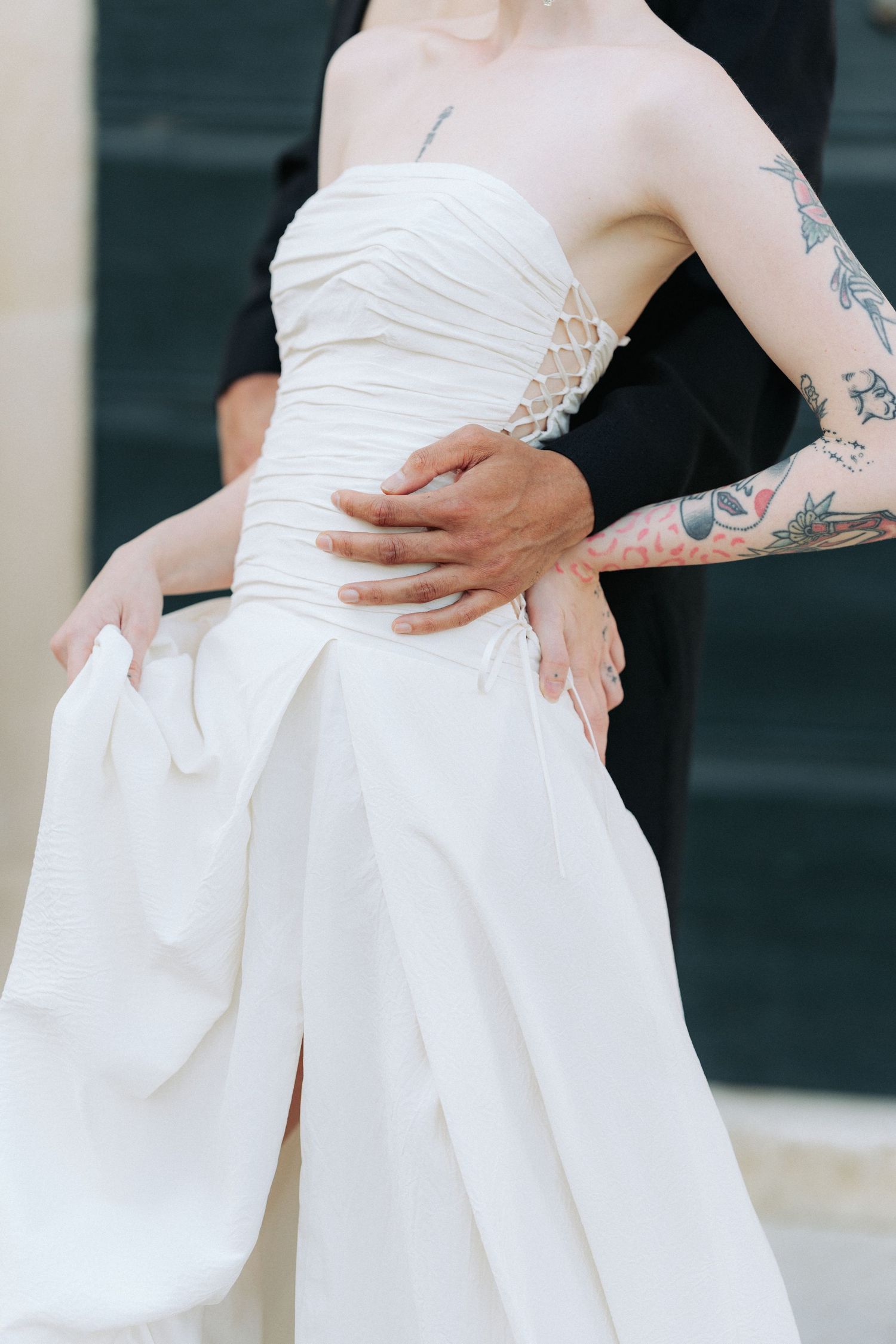 Close-up view of a white wedding dress with pleated details and a bow tied at the waist.