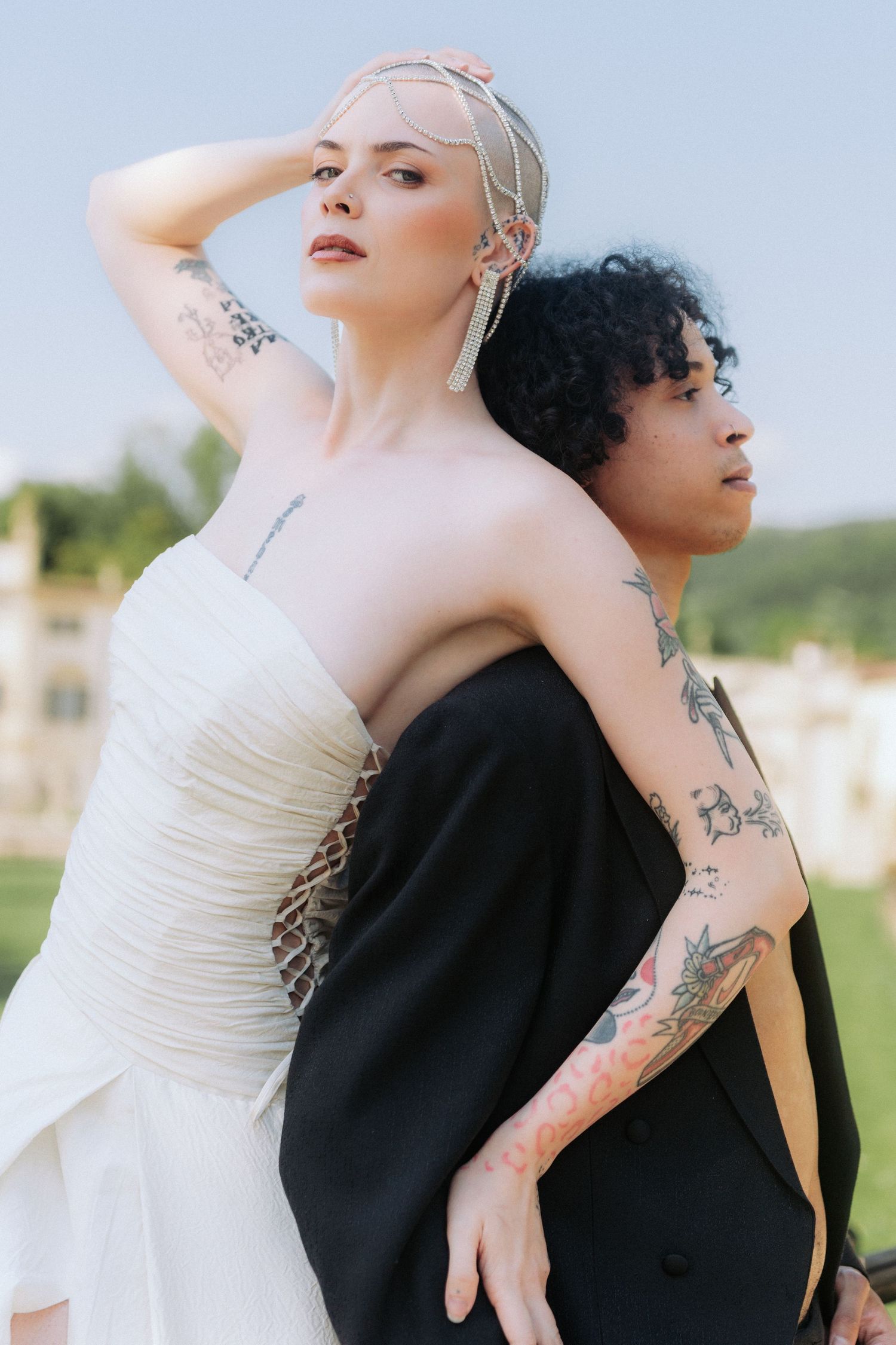 Two people in contrasting black and white outfits pose together in an artistic outdoor photoshoot.