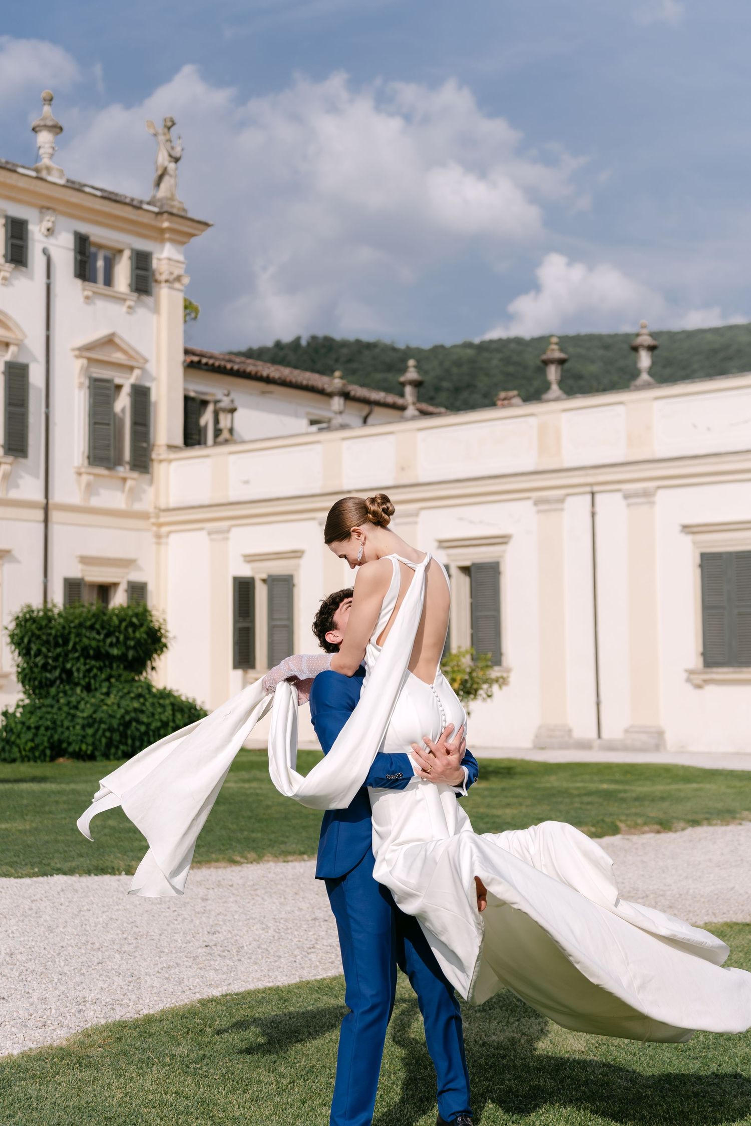 A romantic wedding moment captured in front of an Italian villa with flowing white dress fabric.