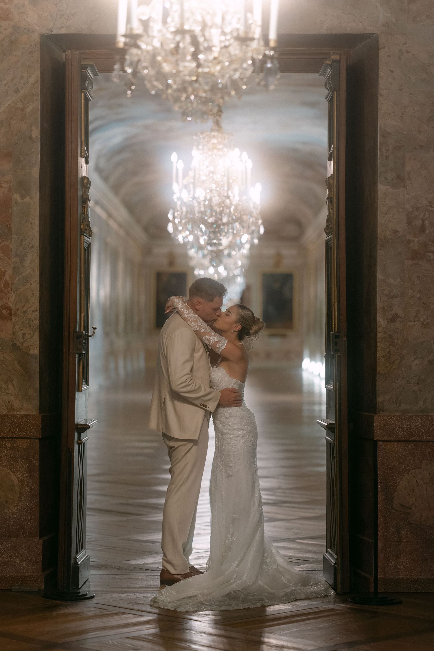 A romantic couple dances together in an elegant hallway with crystal chandeliers and marble columns. Schloss Ludwigsburg