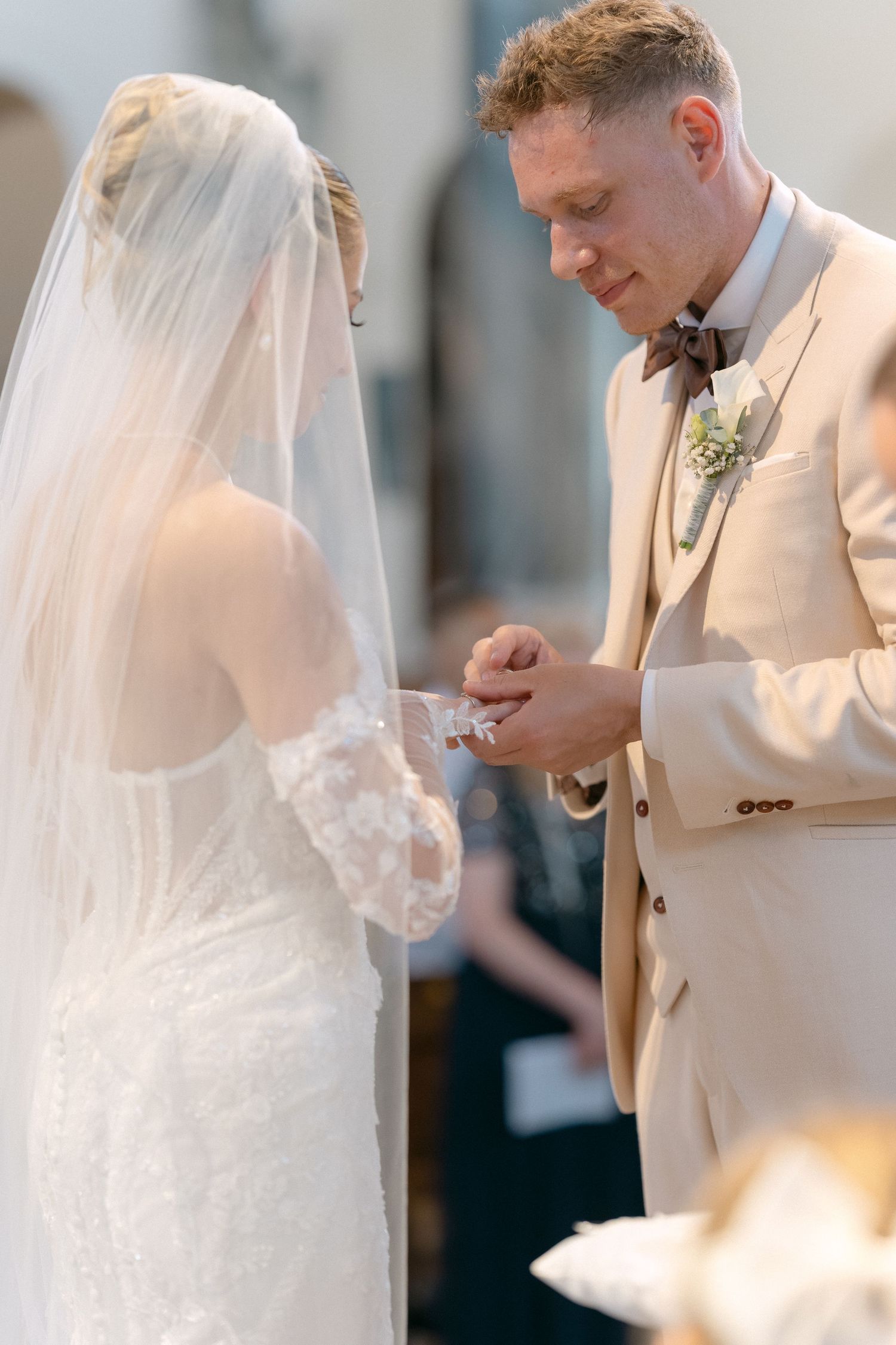 A bride and groom share an intimate moment during their wedding ceremony, with soft lighting and elegant attire.