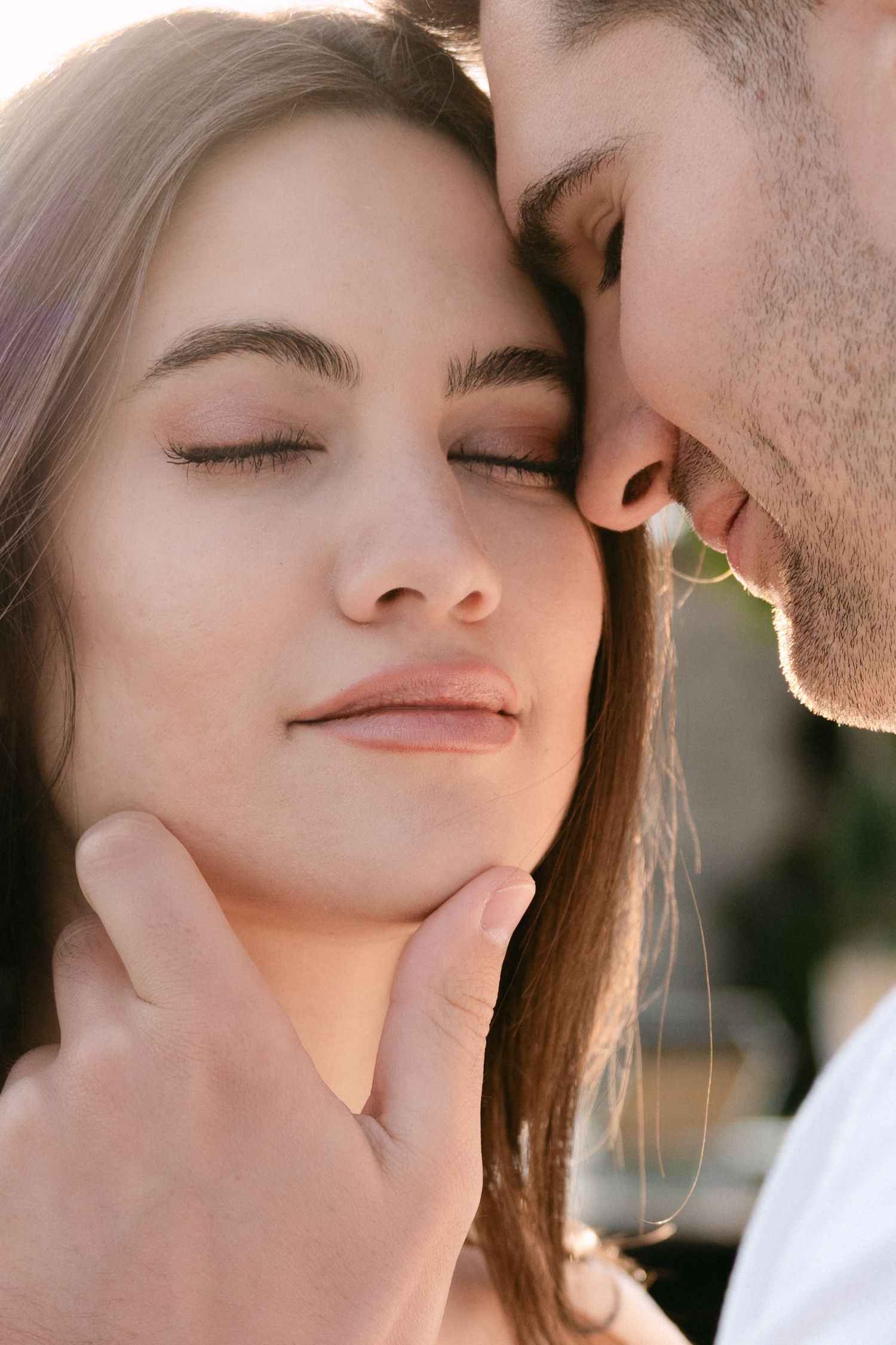 Close up romantic portrait of couple sharing an intimate moment with eyes closed and gentle touch.