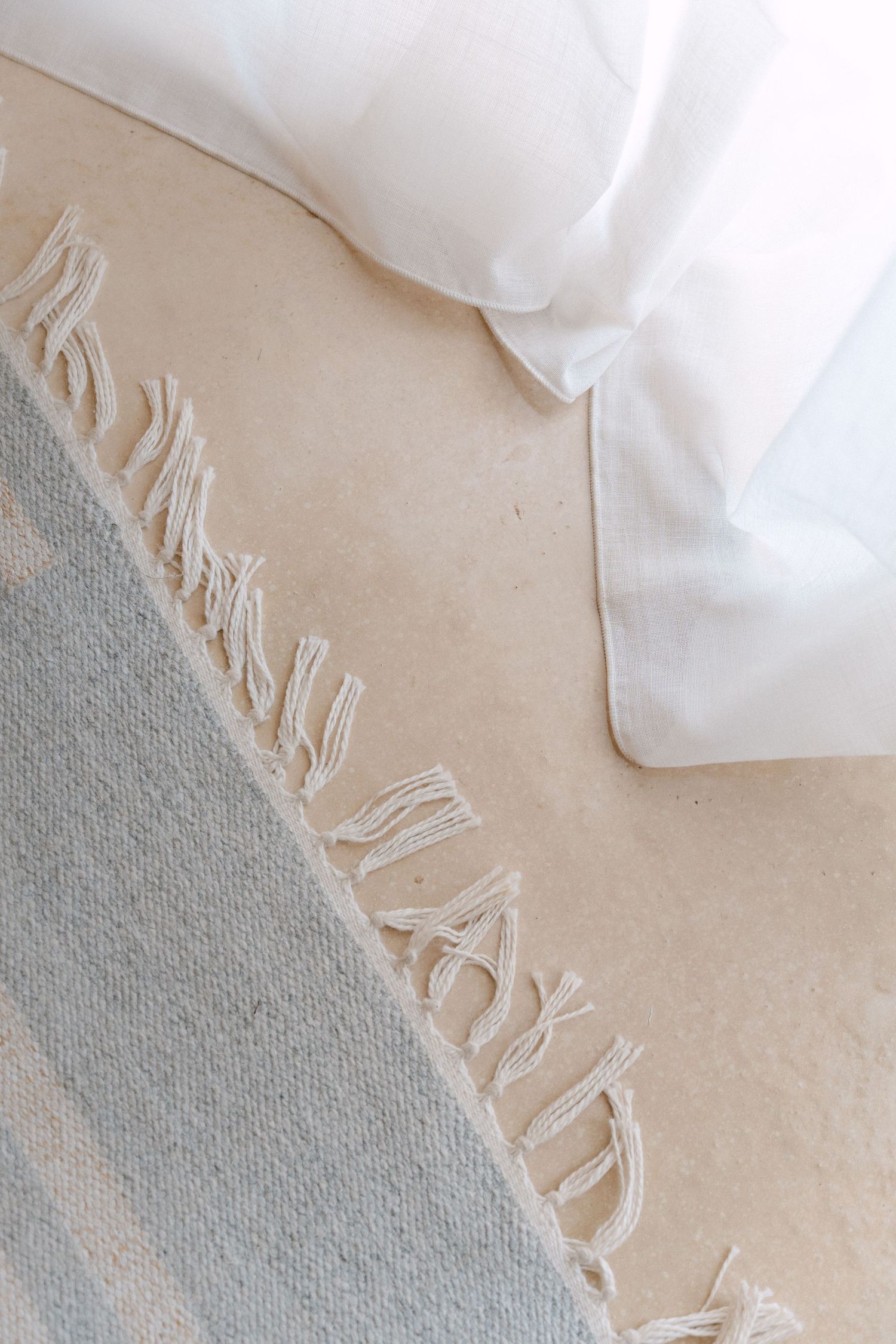 White textured fabric with fringe detail against a gray surface.