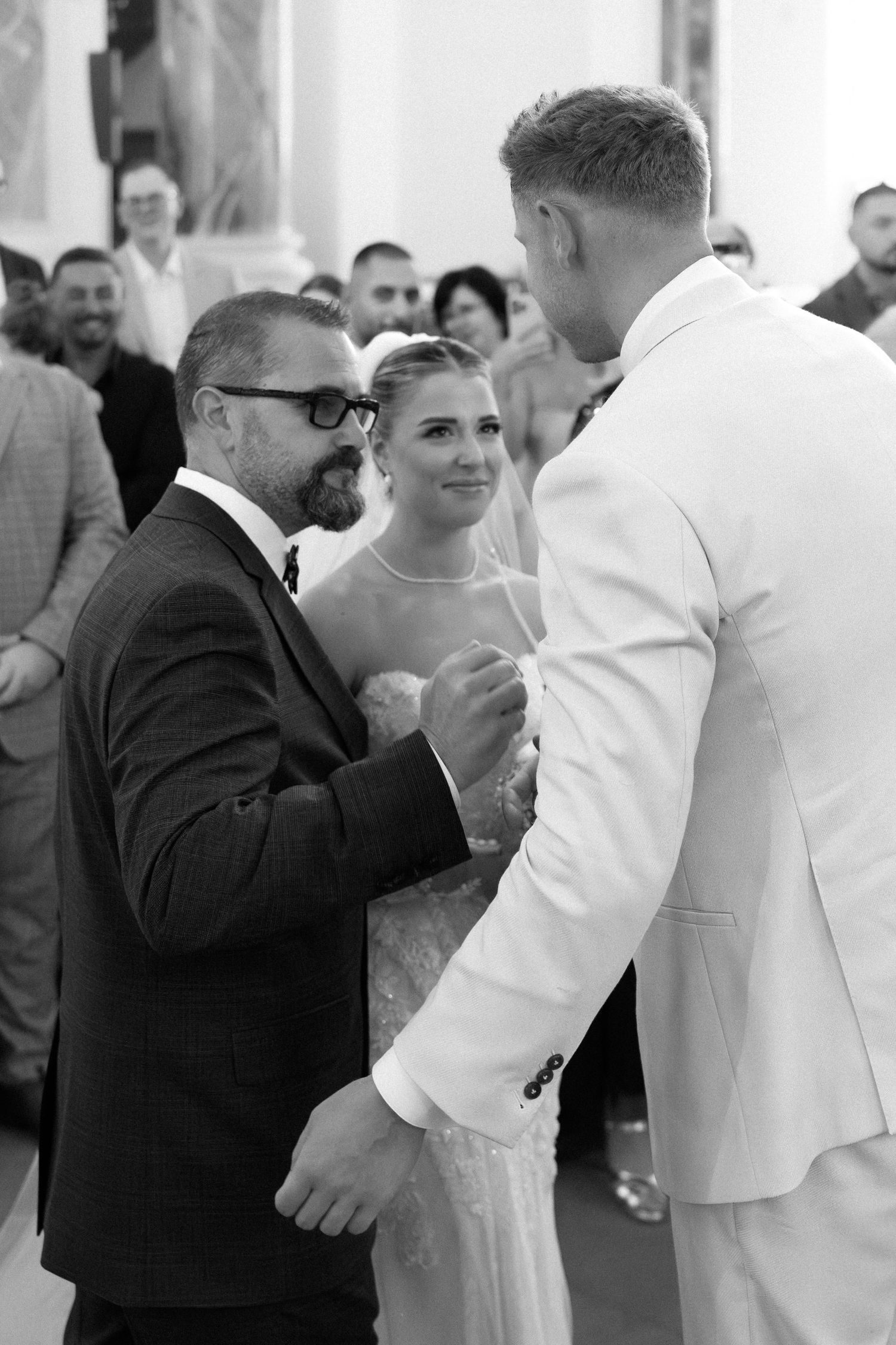 Black and white photo of a wedding ceremony with guests gathered around during an intimate moment.