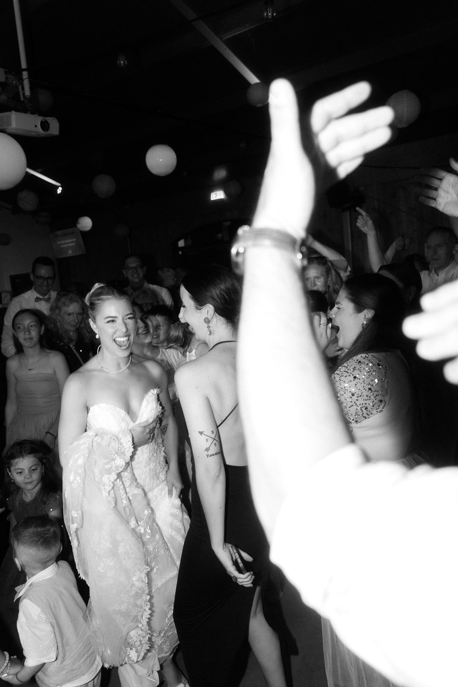 People dancing and celebrating at a lively party with a dark nightclub atmosphere and bright flashes of light.