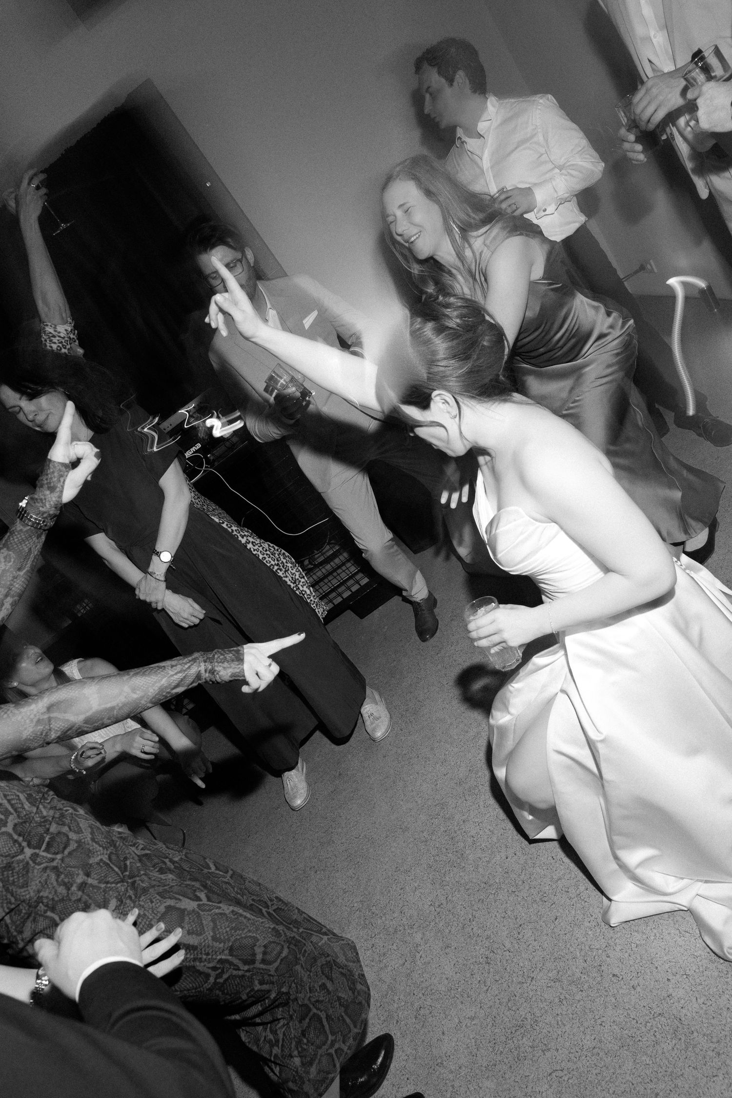 Black and white photo of wedding guests dancing energetically on the dance floor during a lively reception celebration.