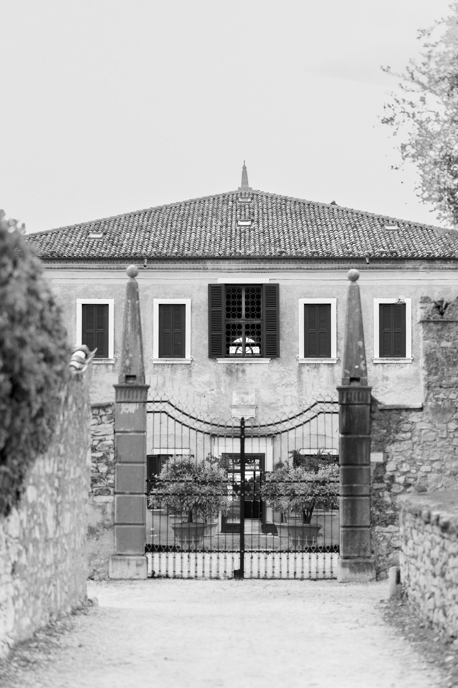 Three black and white photos show a historic stone entrance gate with ornate ironwork and white pillars at different angles.