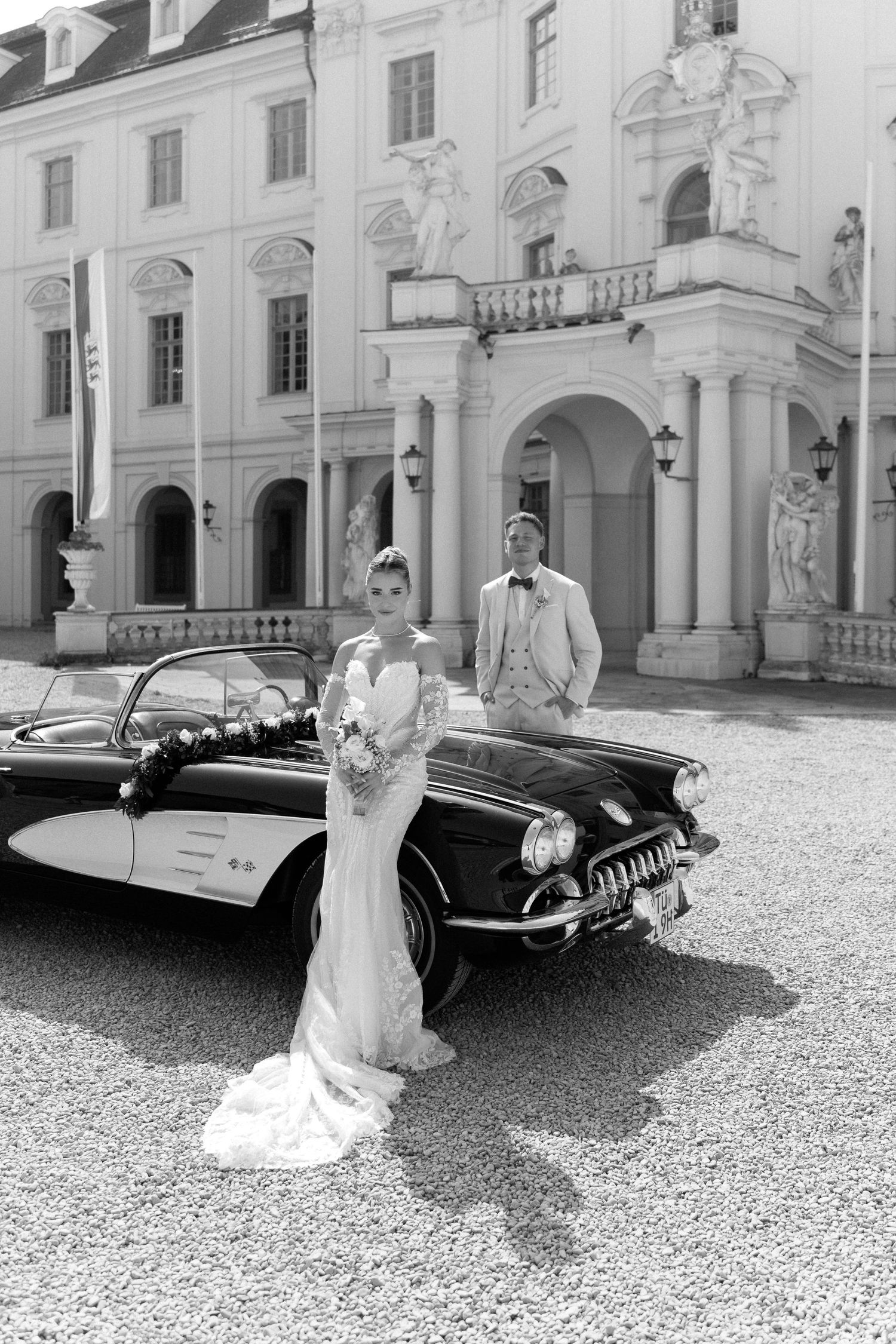 A classic vintage car is parked in front of an elegant European palace courtyard in black and white photography. Schloss Ludwigsburg