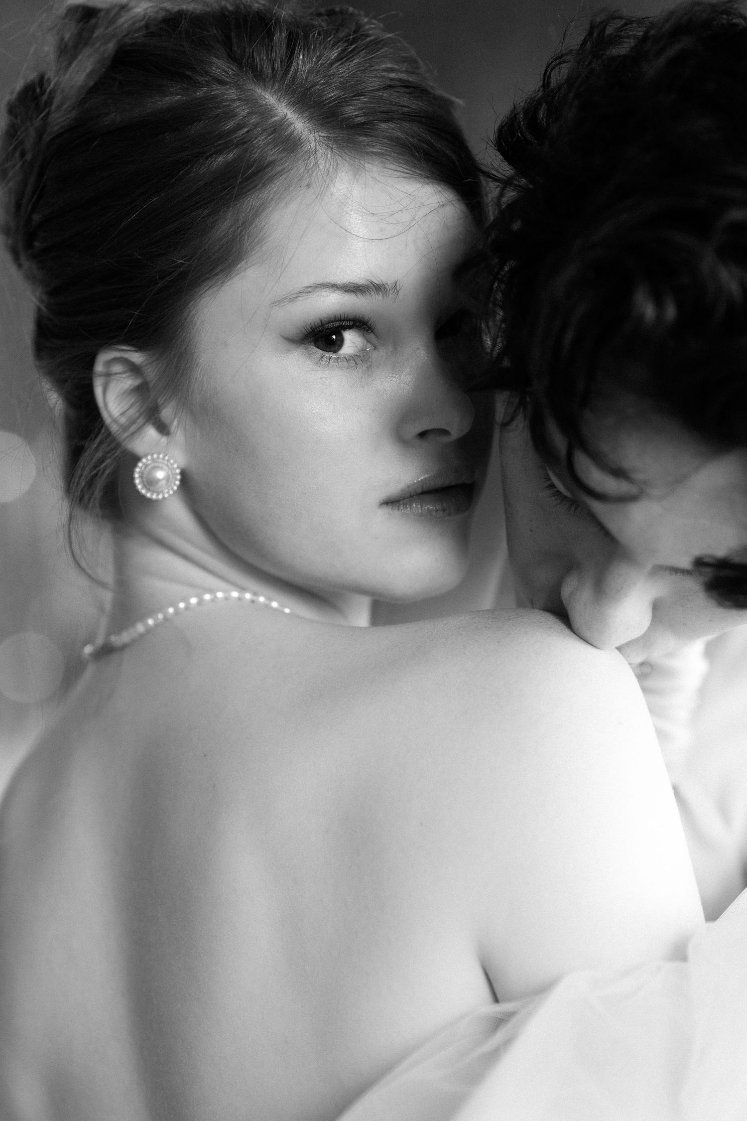 Intimate black and white artistic portrait with dramatic lighting and shadows.