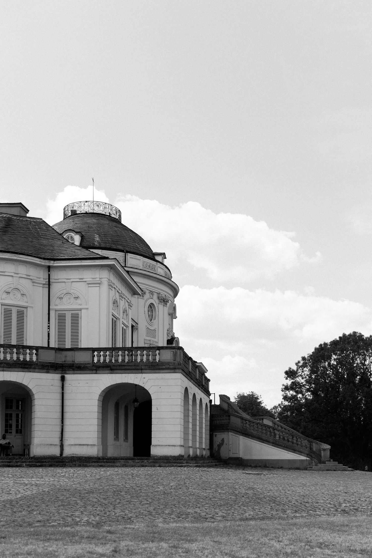 Black and white architectural photos showing a historic mansion with arched windows and balconies on a grassy hillside. Schloss Solitude