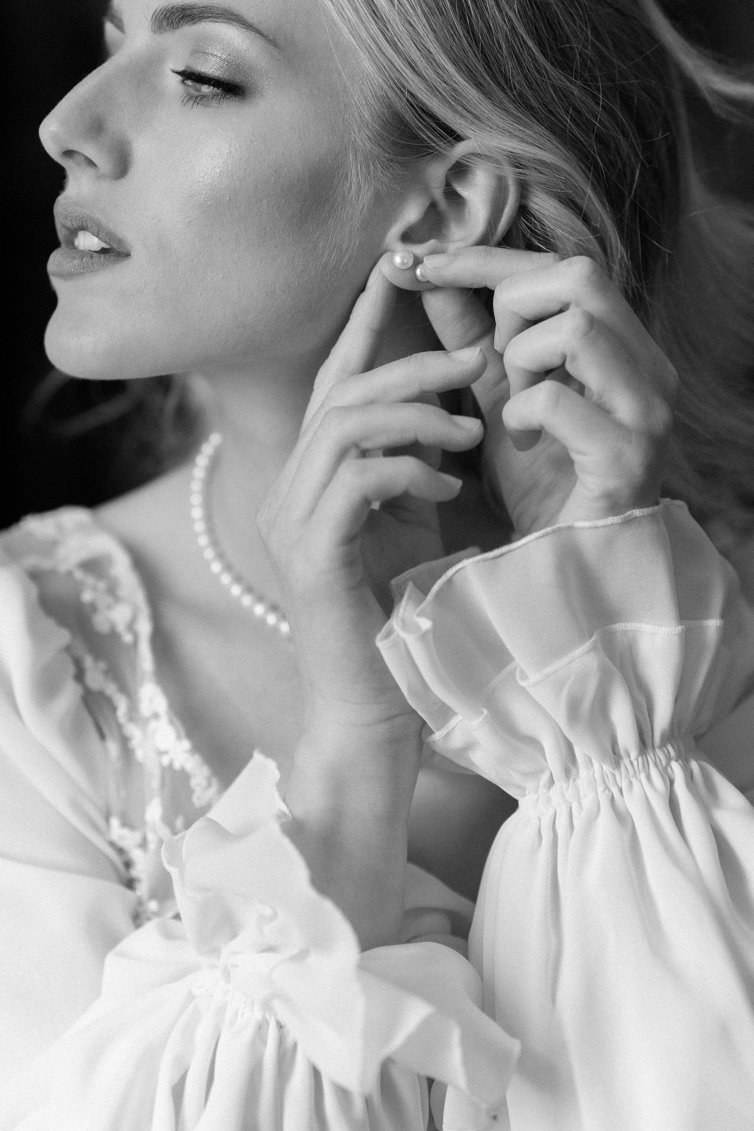 Black and white artistic portrait series showing elegant poses in white ruffled blouse with pearl necklace. Wedding Verona