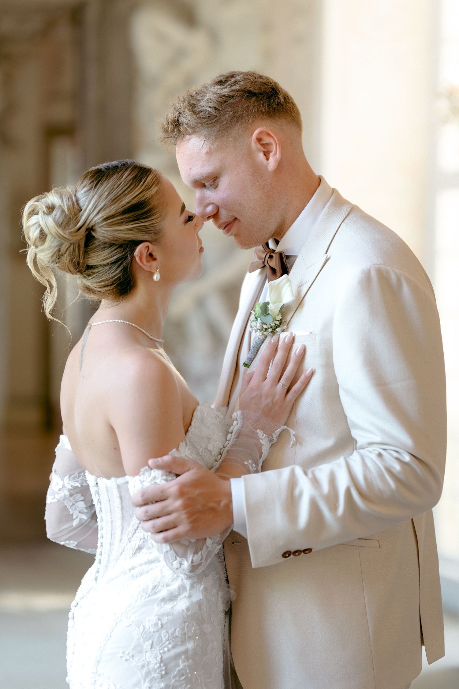 A romantic wedding moment between a couple in formal attire, with the bride in lace and groom in light beige suit. Schloss Ludwigsburg