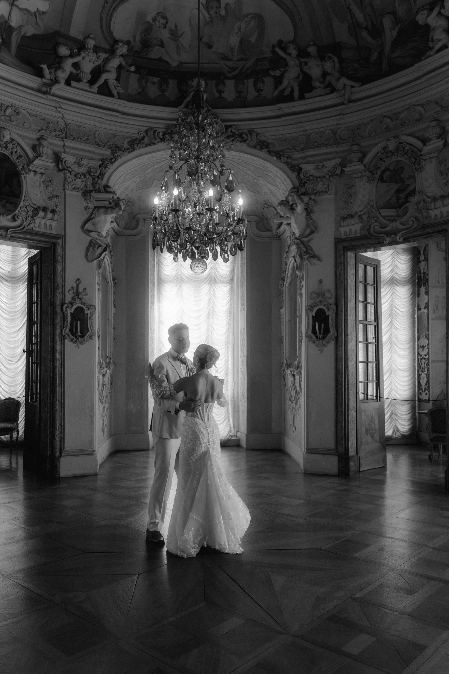 Elegant couple dancing in a grand baroque ballroom with ornate chandeliers and classical architecture. Schloss Ludwigsburg