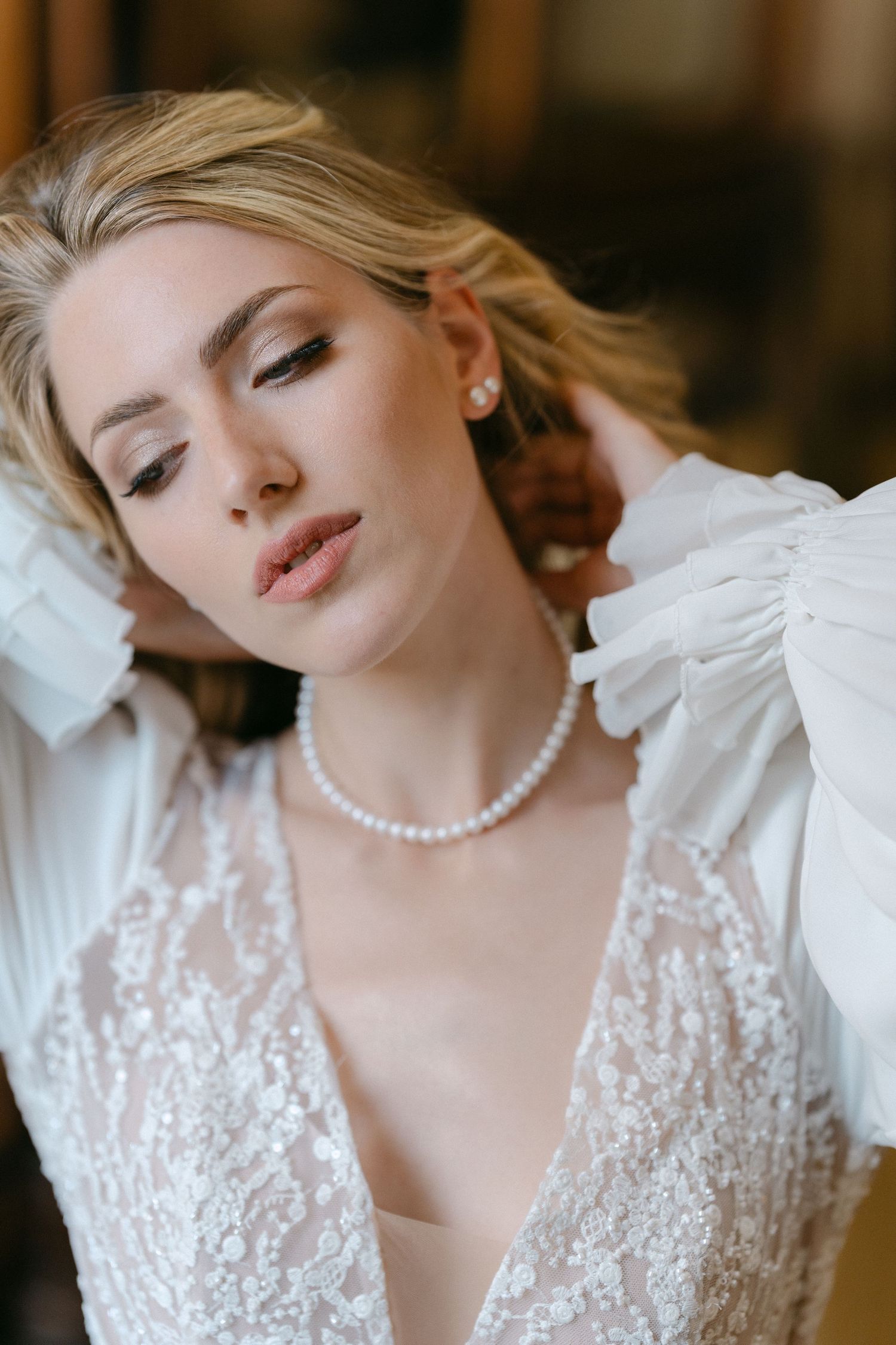Close-up portrait of a bride in white lace dress and pearl necklace with soft romantic styling and makeup. Wedding Verona