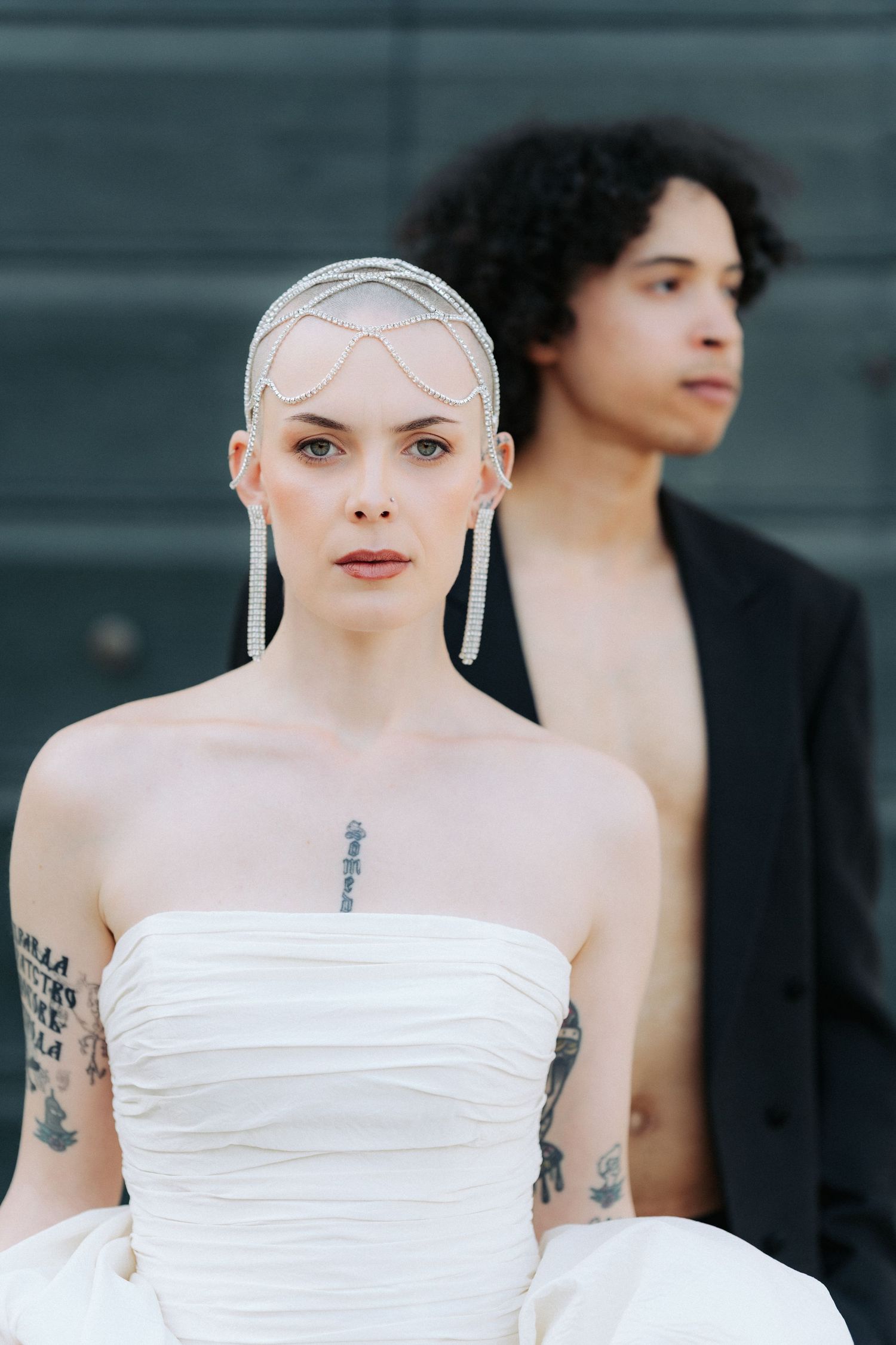 Five close-up portraits showing a model with dark hair and tattoos wearing a white strapless top against a dark background.