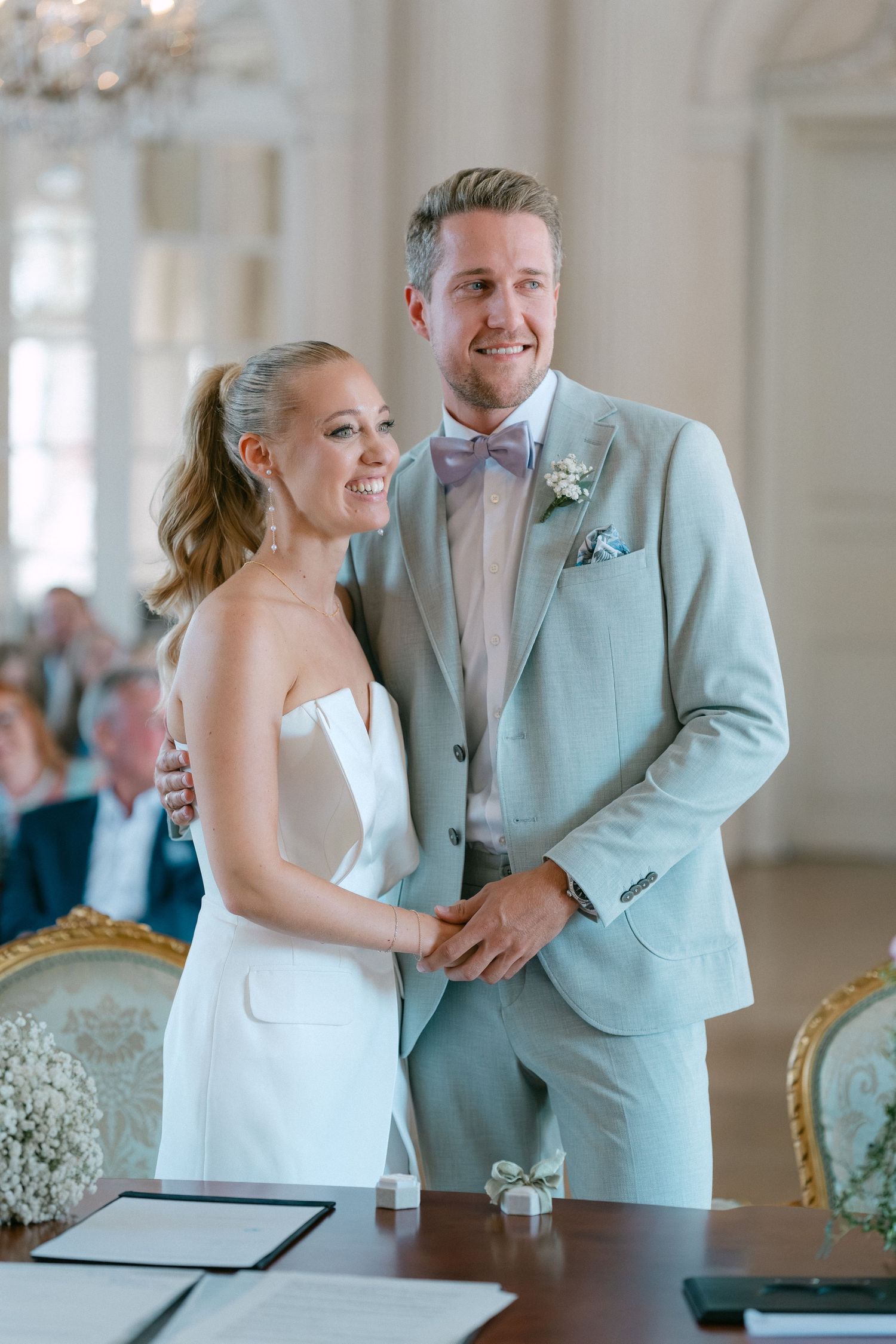 A couple shares a joyful moment while signing their marriage license at an elegant indoor venue. Schloss Solitude
