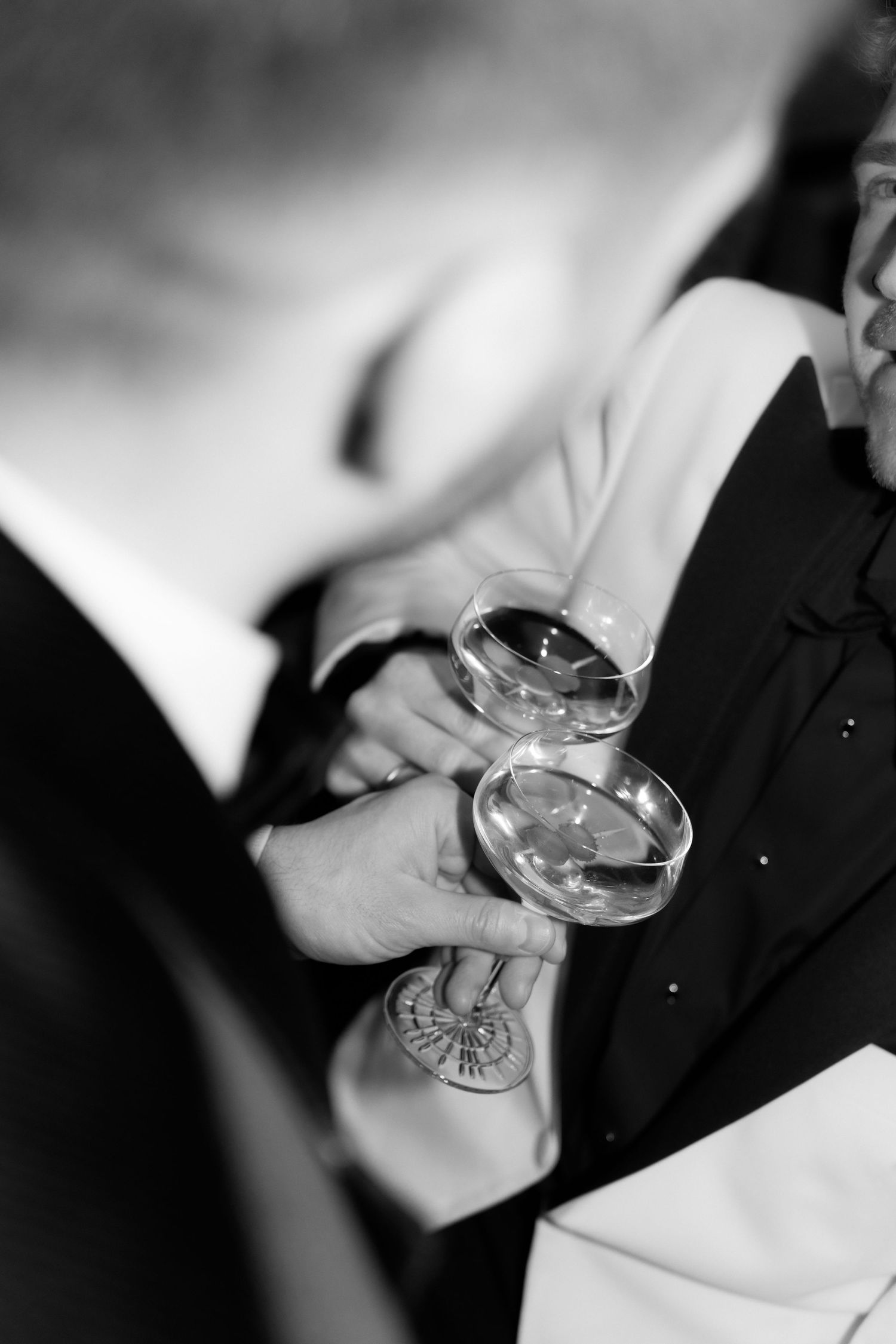 Two people clink their champagne glasses together in an elegant black and white celebration moment.