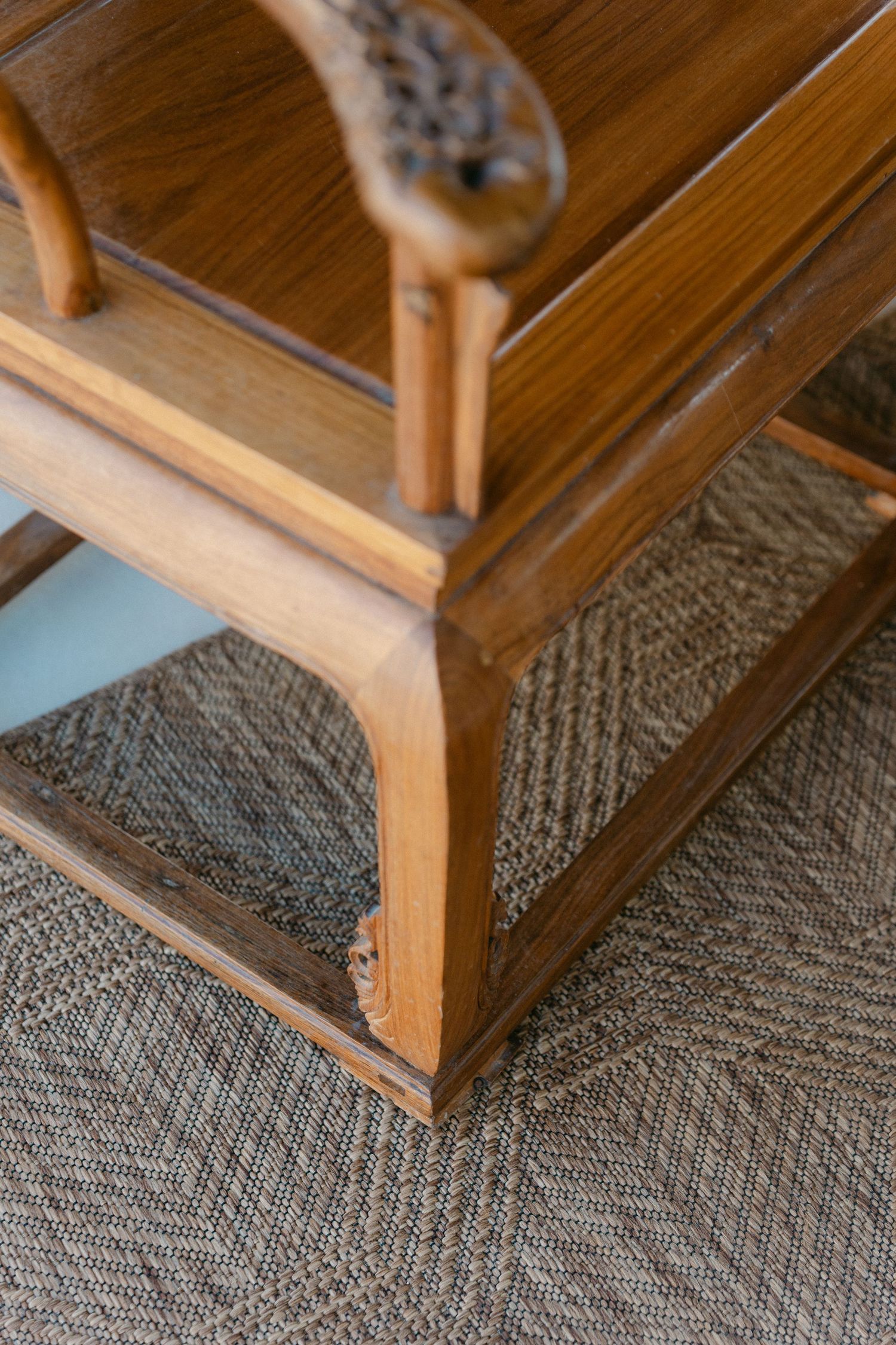 Close-up of wooden stairs with a textured gray carpet runner.