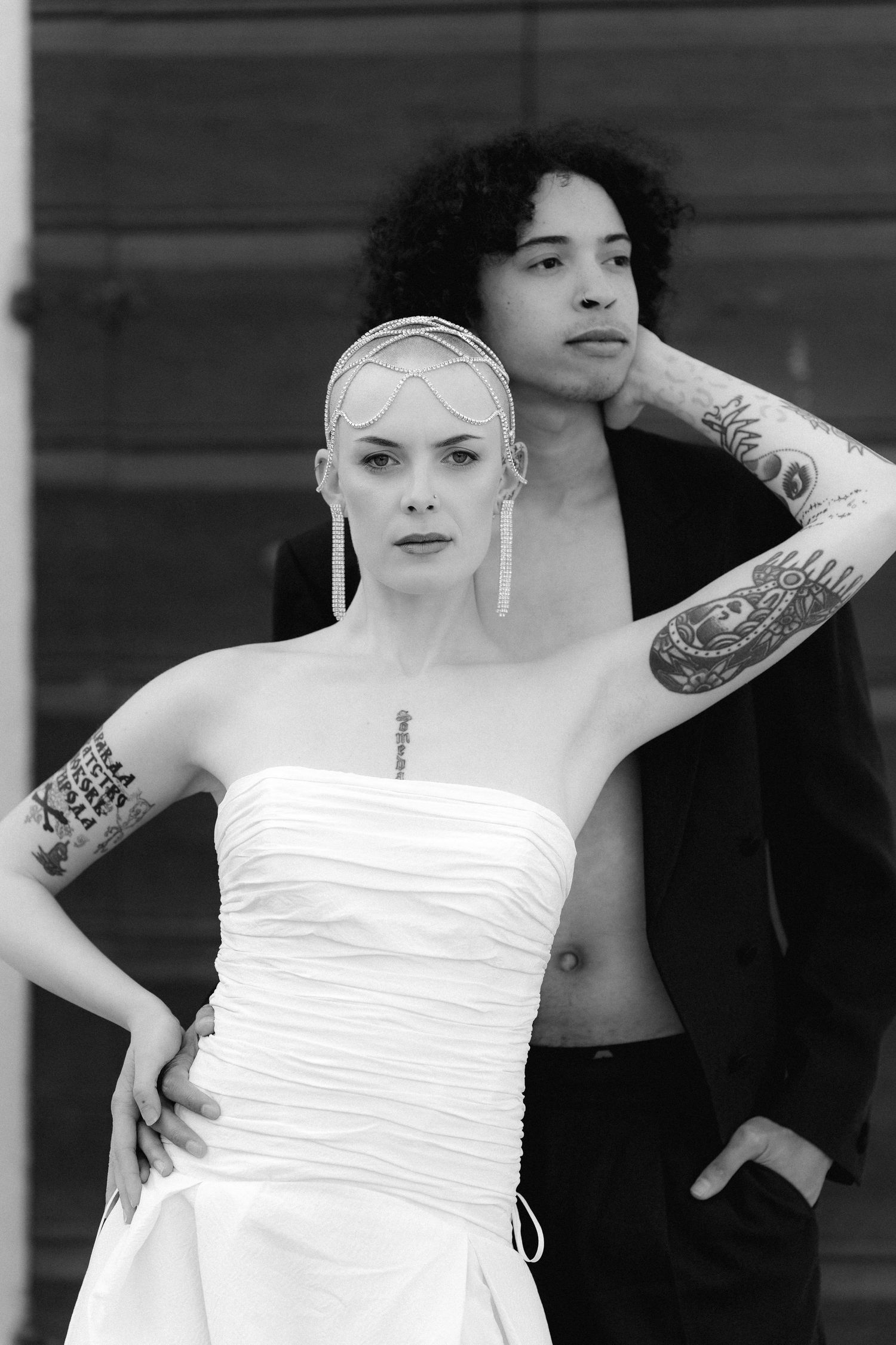 Black and white photo series showing someone in a white strapless dress posing with tattoos visible on their arms.
