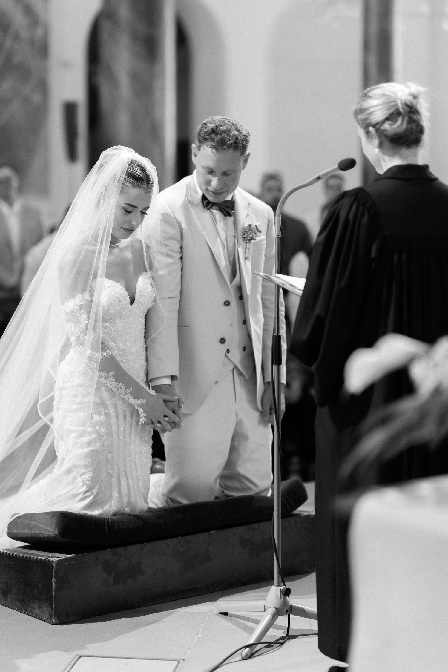Black and white wedding ceremony sequence showing couple signing documents at altar with officiant present.