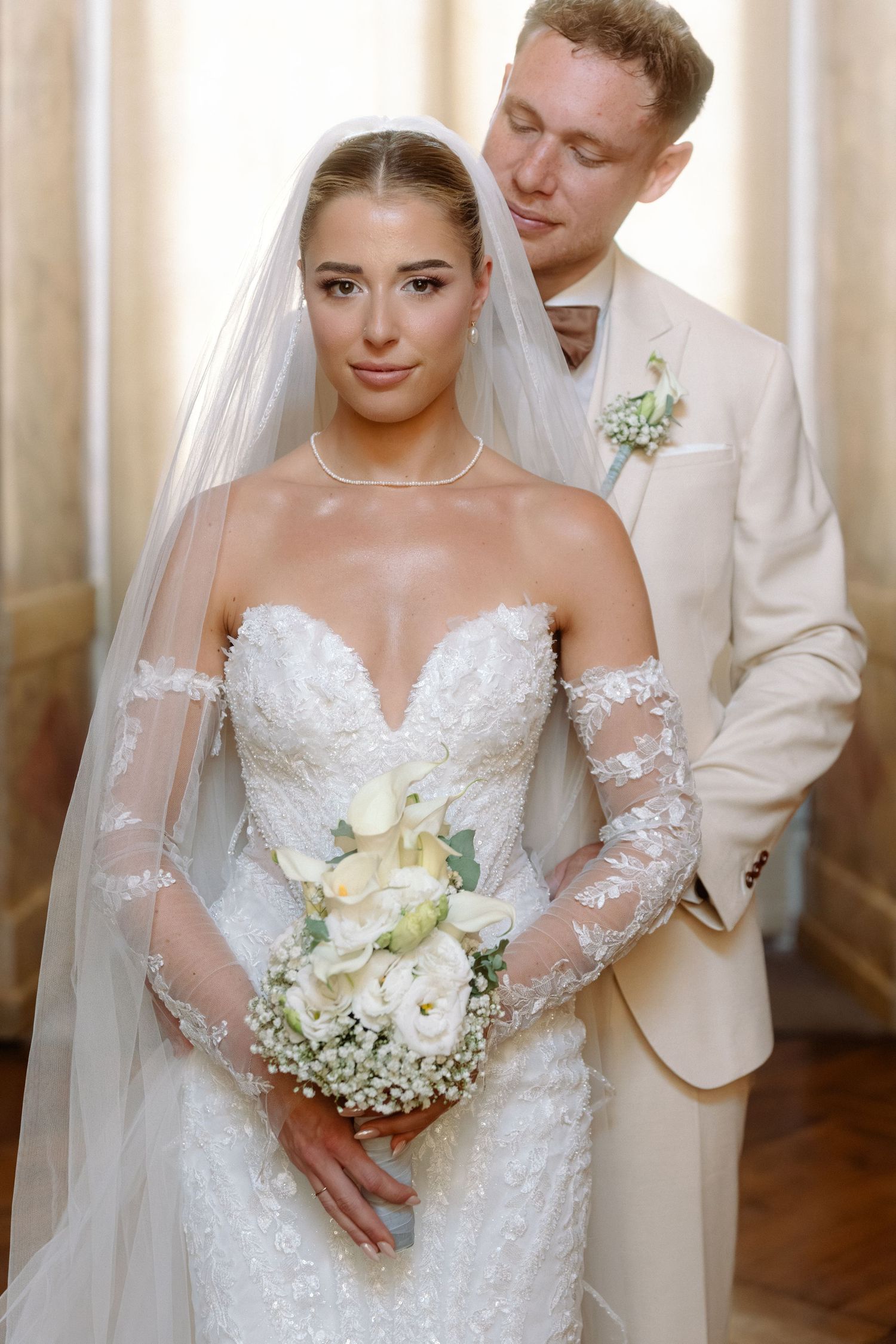 A wedding couple stands together in formal attire with the bride holding a white and yellow floral bouquet. Schloss Ludwigsburg
