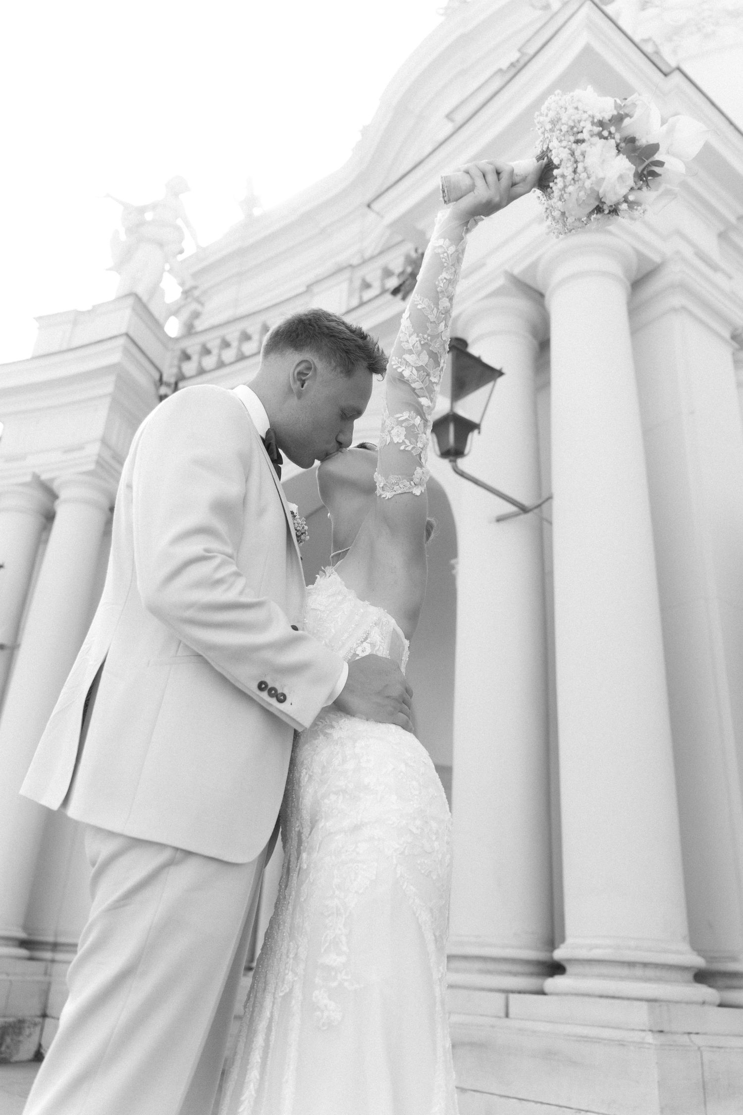 A romantic wedding couple shares intimate kisses in front of elegant white columns in a series of photos. Schloss Ludwigsburg